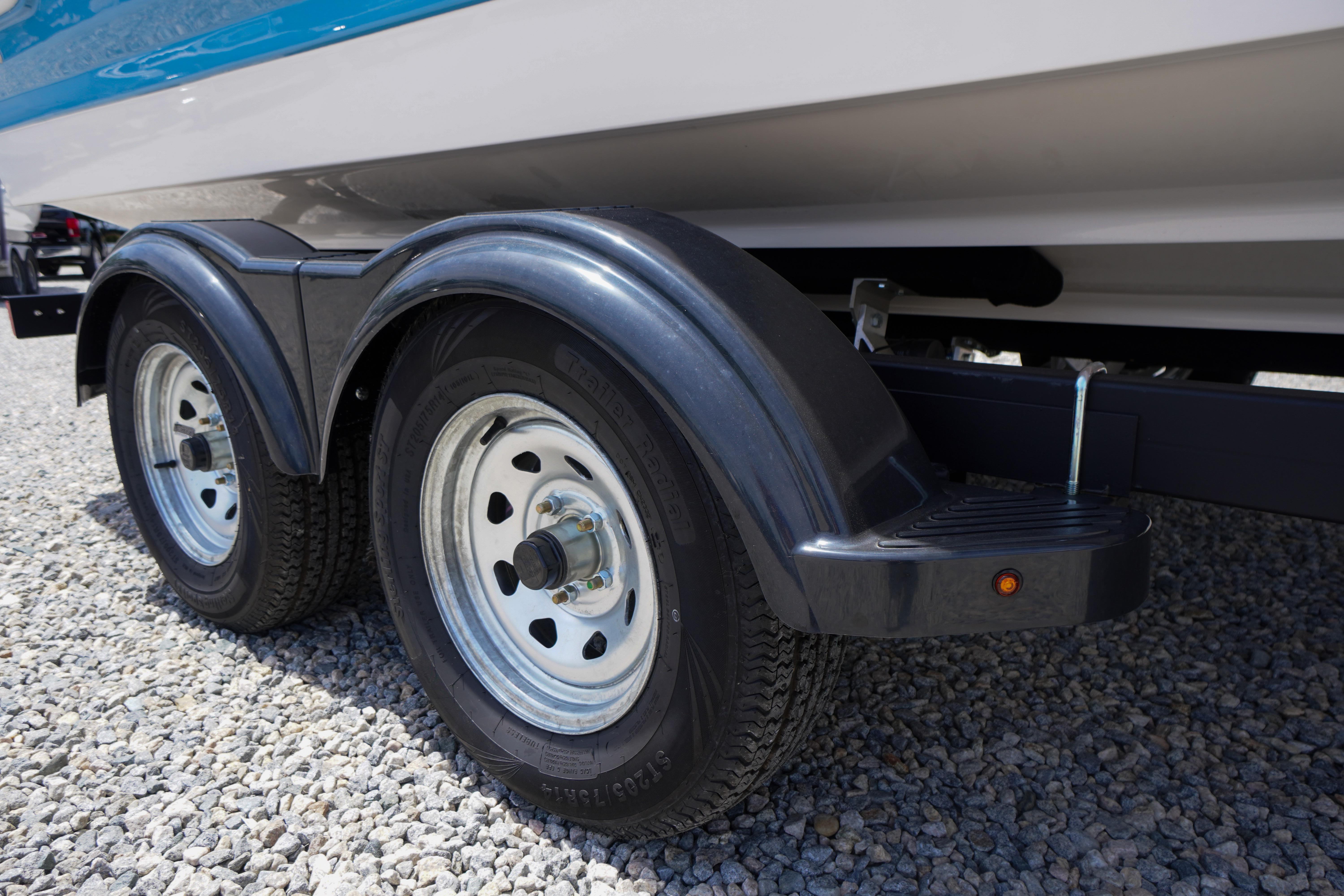 Trailer wheels of 2026 Chaparral 23 SSi OB boat on gravel surface.