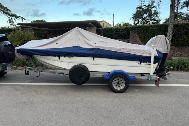 2016 Boston Whaler 150 Montauk boat covered on trailer, parked on street.