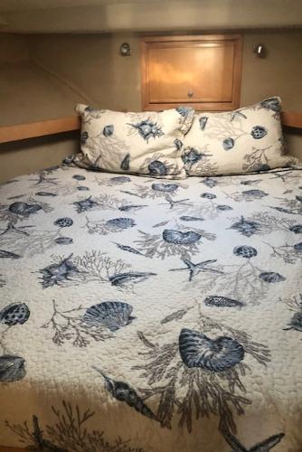 Cozy bedroom in a 1997 Bertram Convertible boat with seashell-themed bedding.