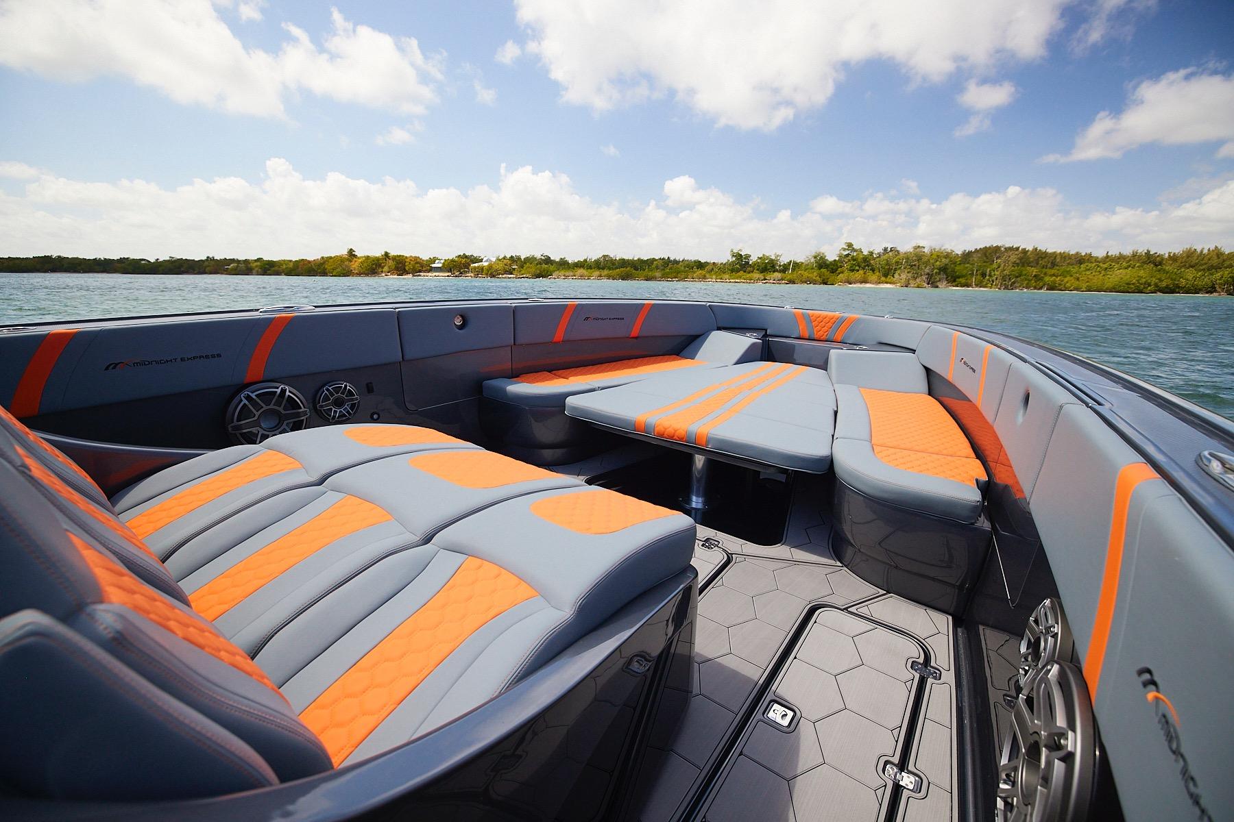 Luxurious 2022 Midnight Express 43 Open boat interior with orange and gray seating on a sunny day.