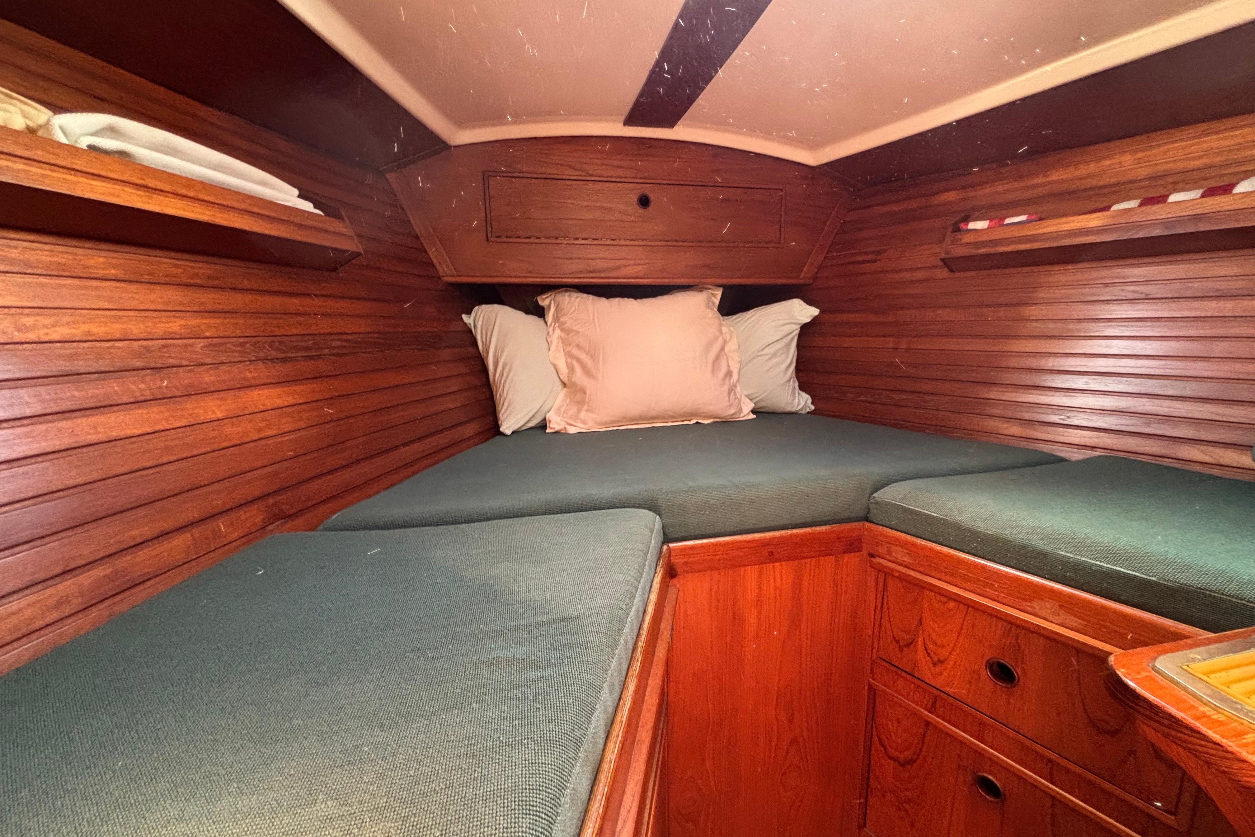 Cozy cabin interior of 1985 Wauquiez Amphitrite sailboat with wooden paneling and cushioned berth.