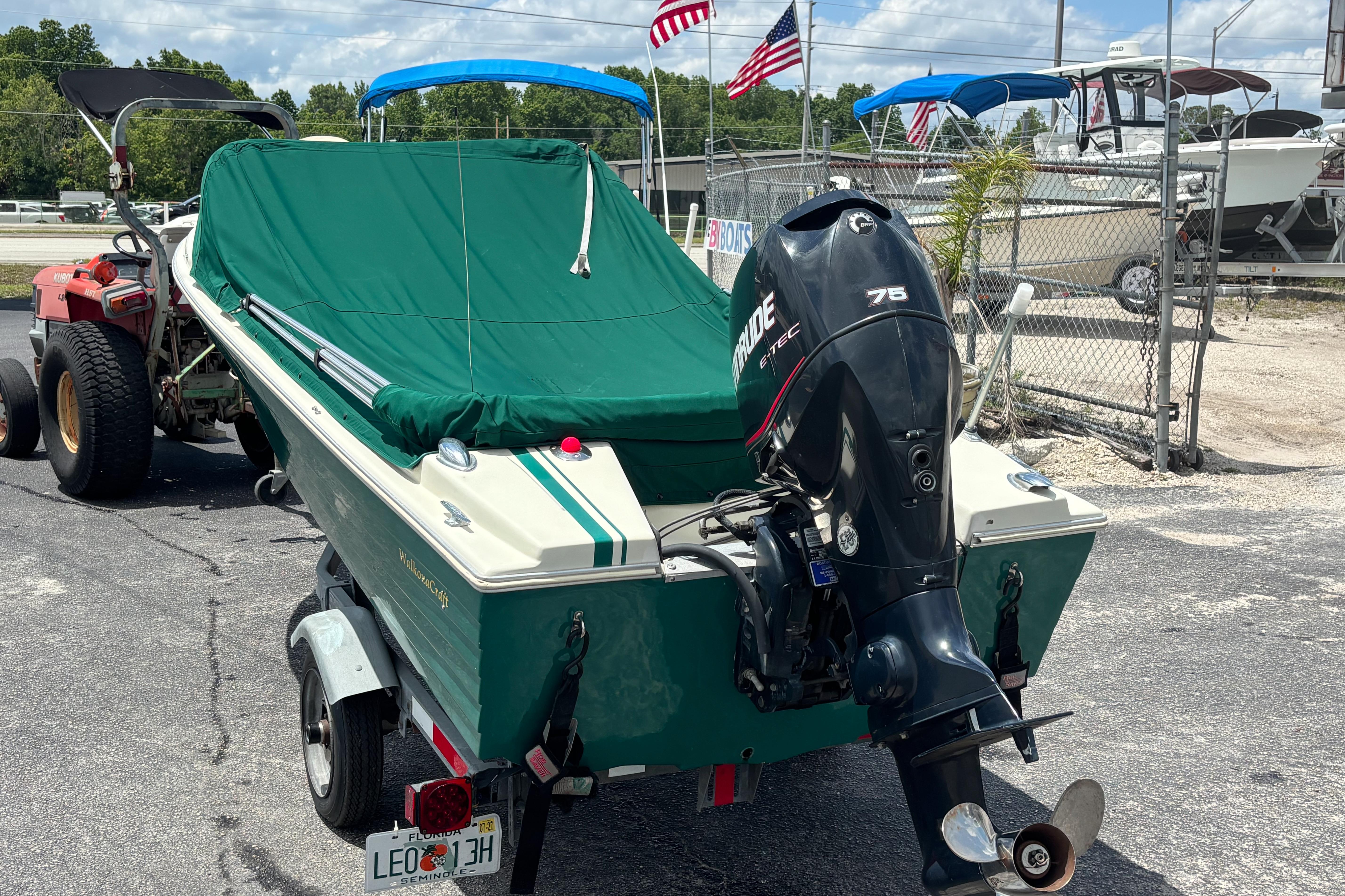 1966 Mohawk 15 boat with green cover and Evinrude motor, parked on trailer.