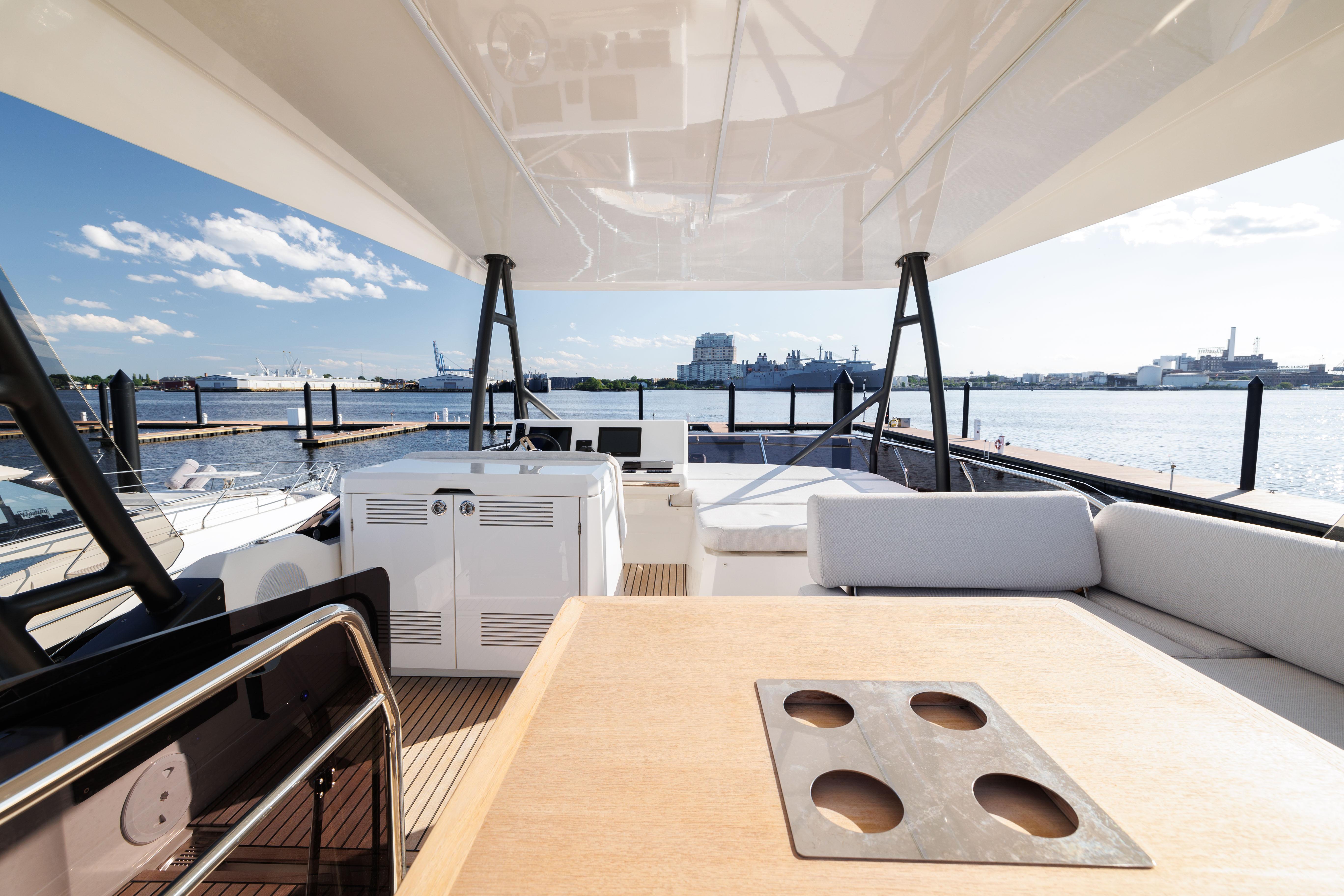 2024 Prestige 520 yacht deck with seating and table, overlooking a scenic waterfront.
