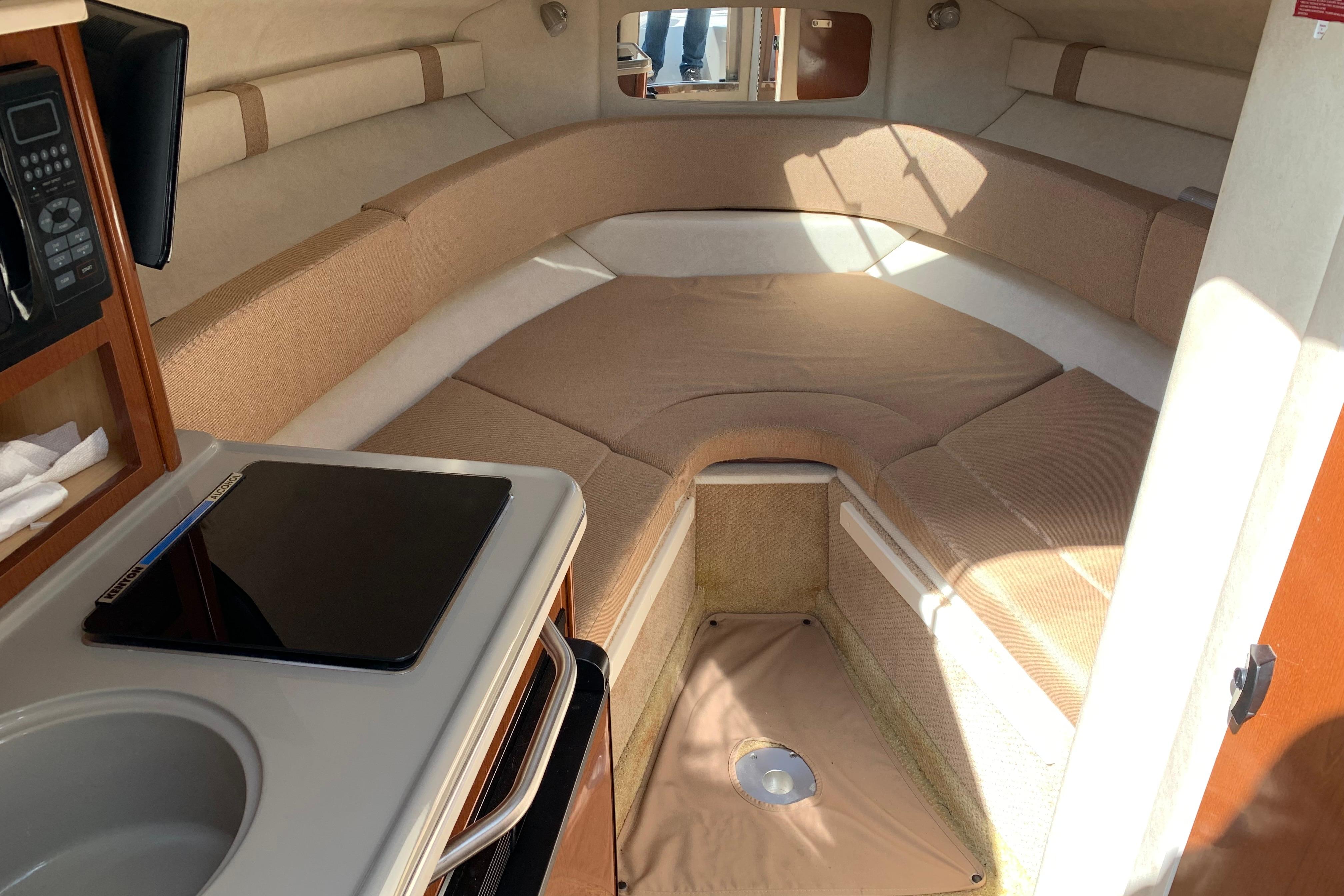Interior cabin of 2012 Sea Ray 240 Sundancer with cozy seating and kitchenette.