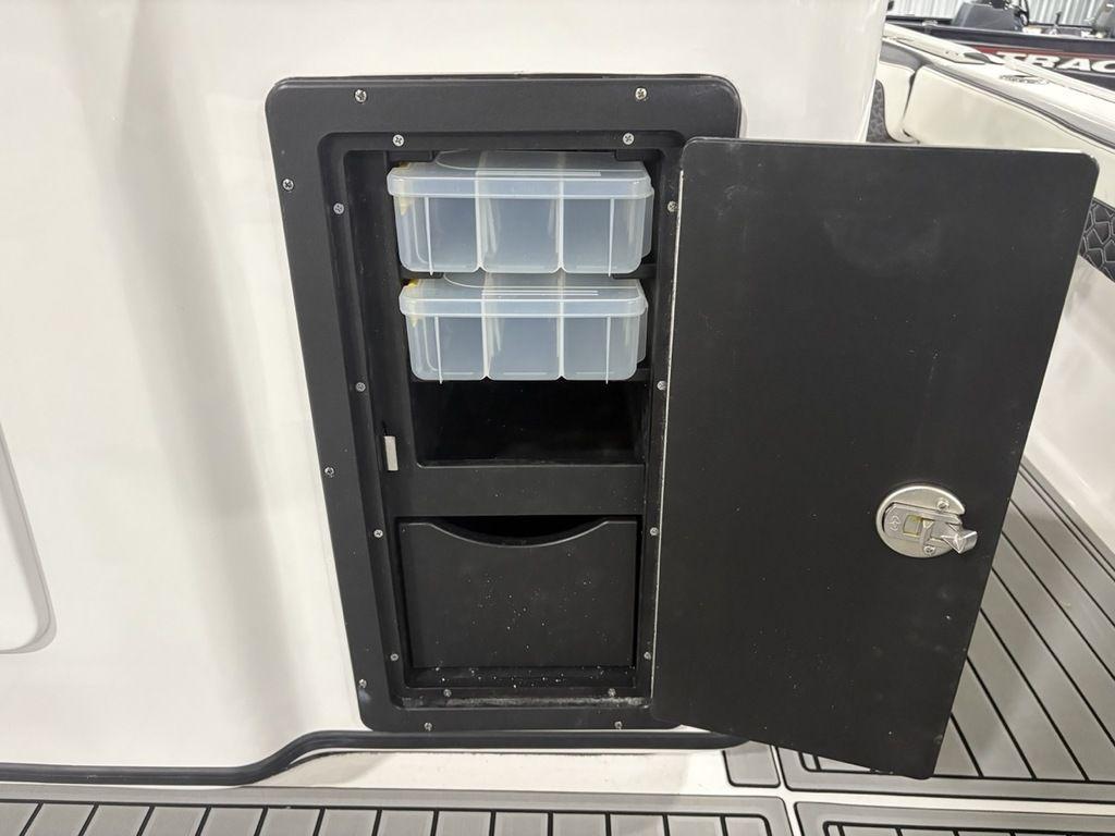Storage compartment on 2026 Tidewater 2700 CB boat with organized plastic containers.