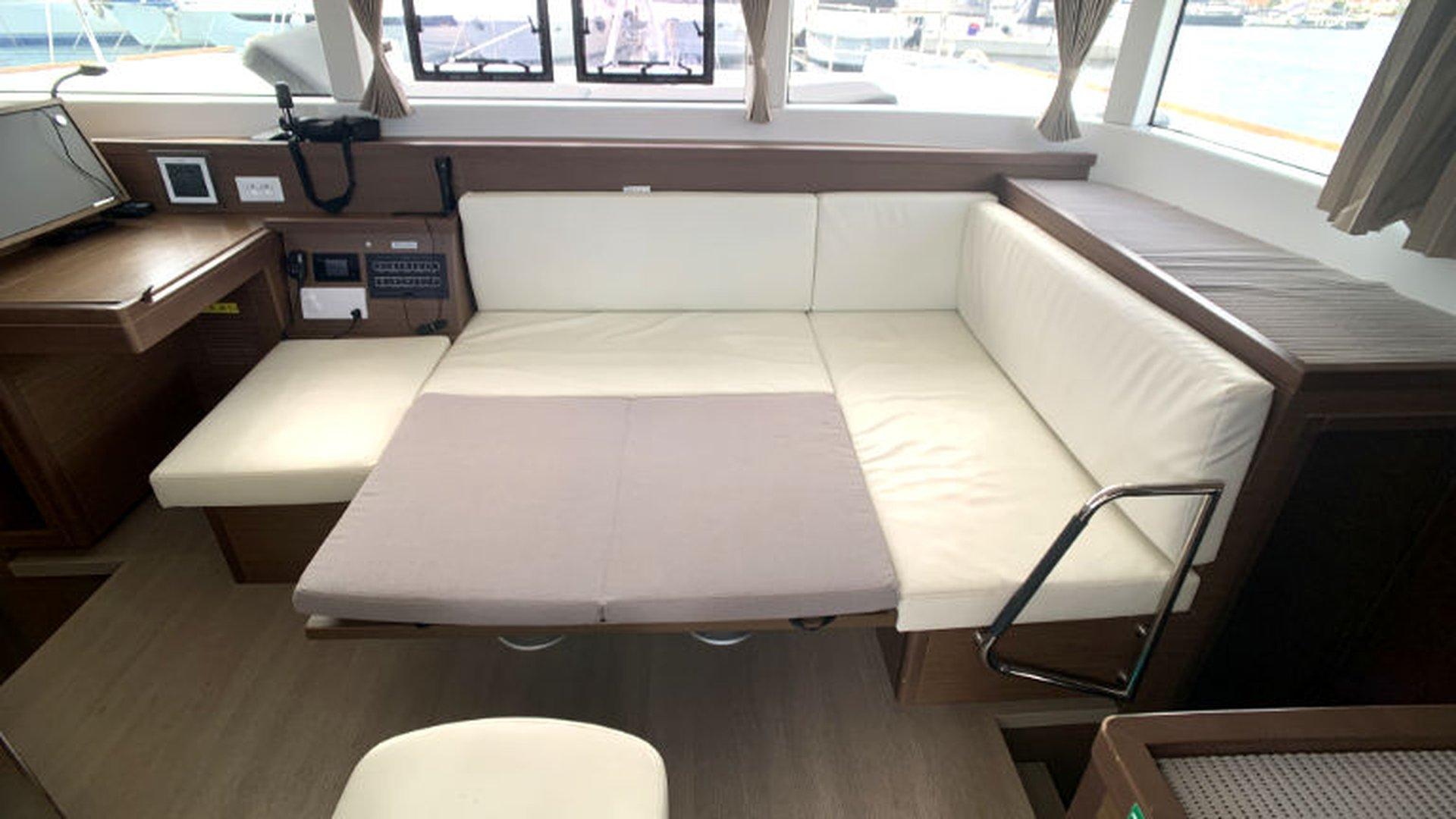 Interior of 2019 Lagoon 40 catamaran with white cushioned seating and wooden accents.