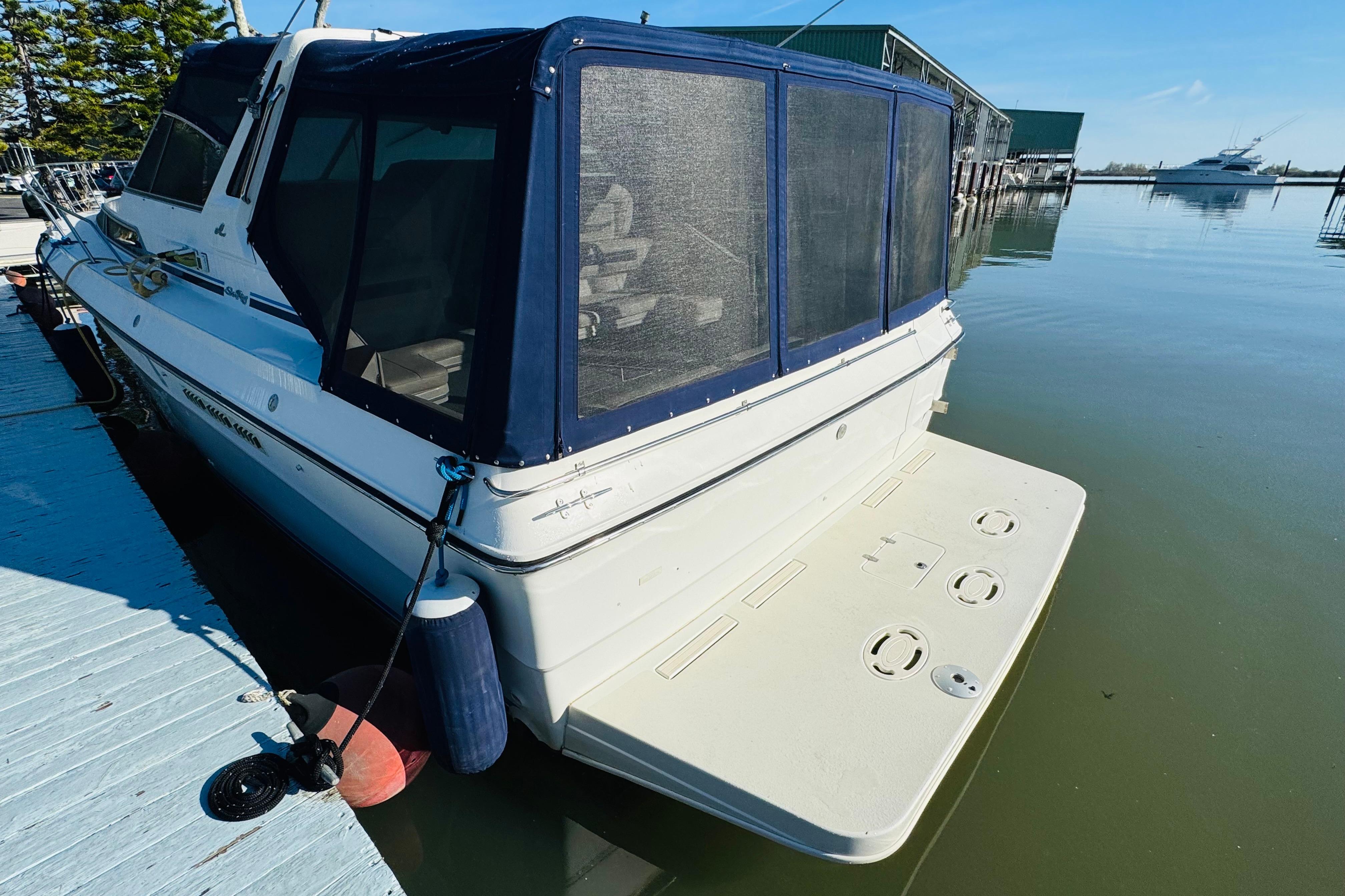 1989 Sea Ray 390 Express Cruiser docked, featuring a covered rear deck and calm waters.