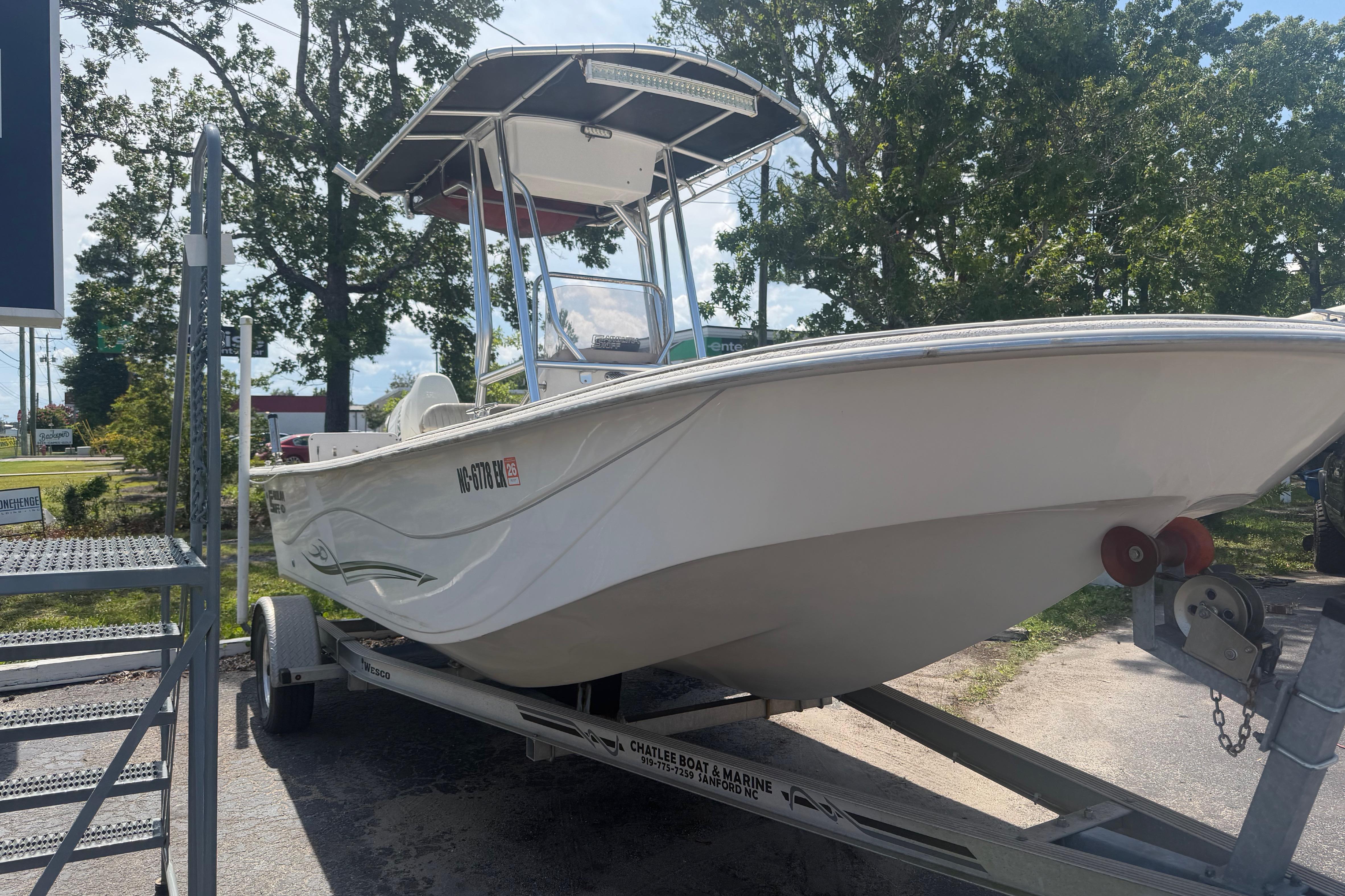 2019 Carolina Skiff 218 DLV boat on trailer, parked outdoors with trees in background.
