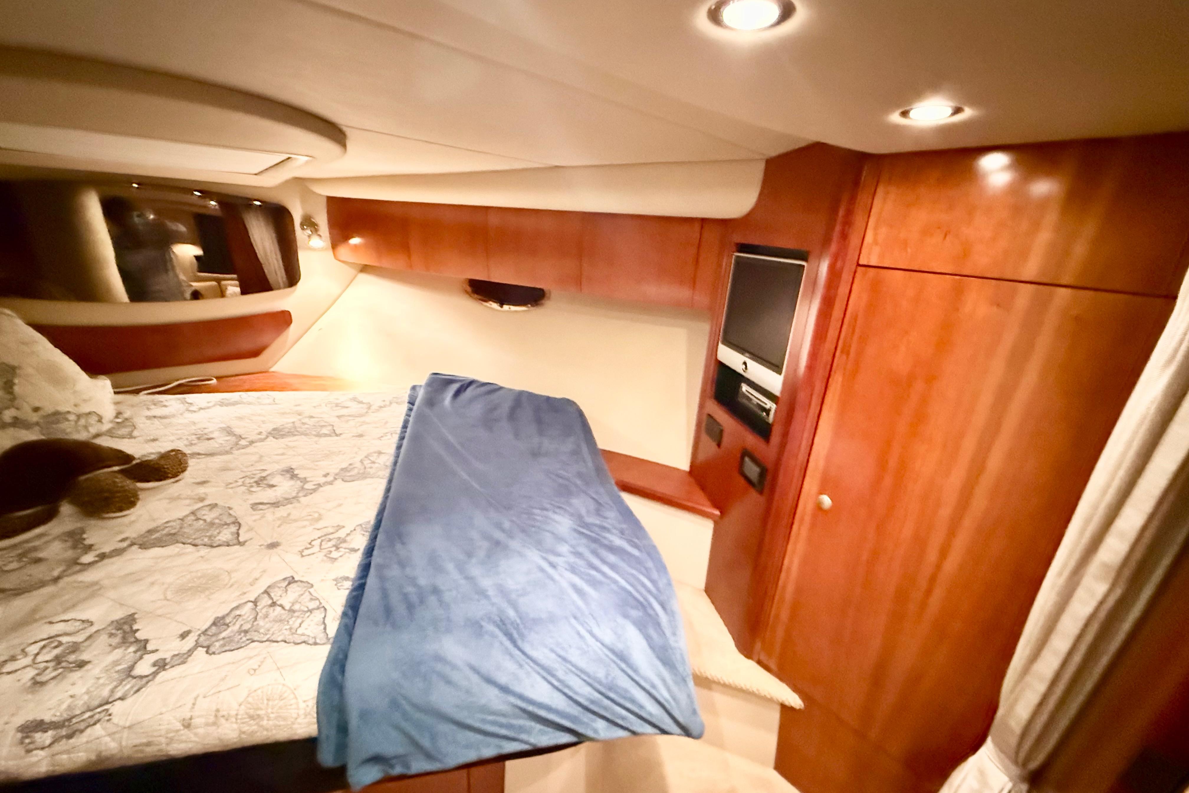 Luxurious cabin interior of 2011 Cruisers Yachts 390 Sports Coupe with wood paneling and cozy bedding.