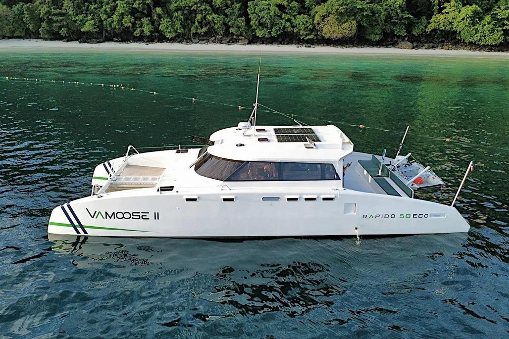 2025 Rapido 500 ECO Power Catamaran on tranquil water near lush shoreline.
