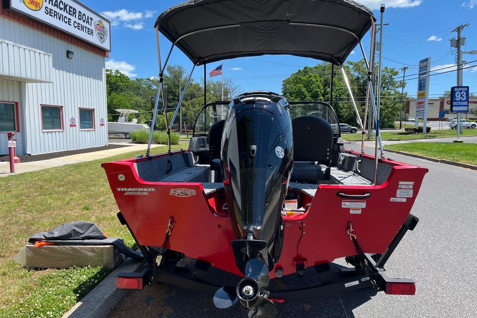 2026 Tracker Pro Guide V-16 WT boat at service center, red exterior, outboard motor.