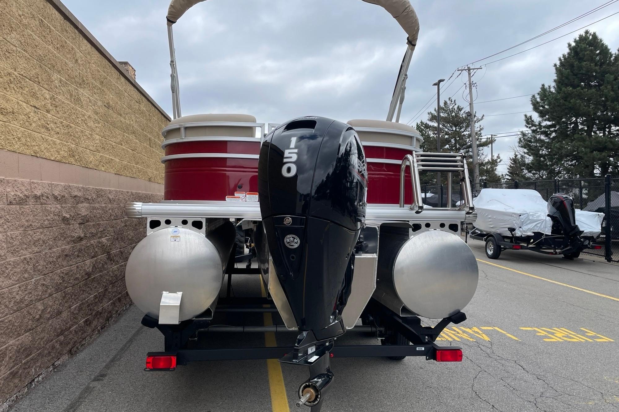 2025 Sun Tracker Party Barge 22 XP3 pontoon boat with 150 HP engine, parked outdoors.