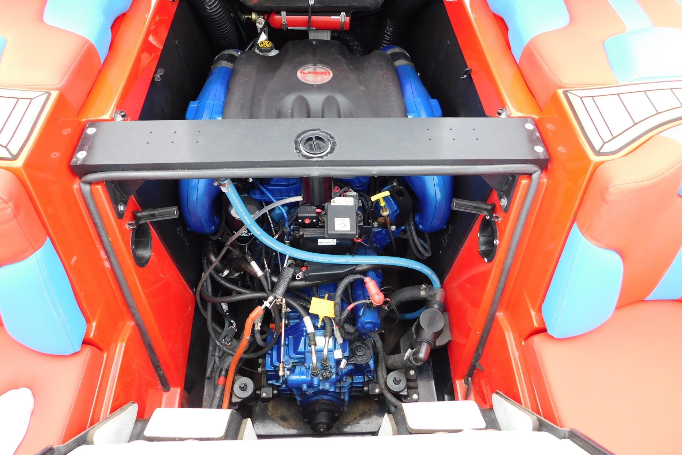 Engine compartment of a 2022 MasterCraft NXT24 boat, showcasing vibrant red and blue accents.