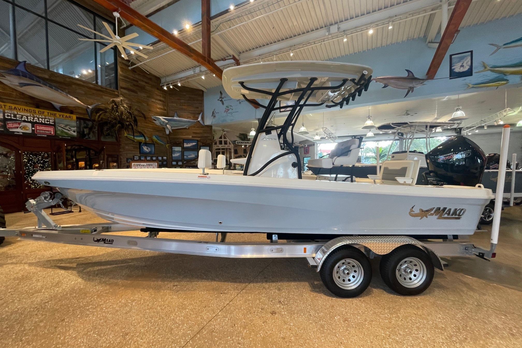 2026 Mako 24 APEX boat on trailer in showroom, side view.