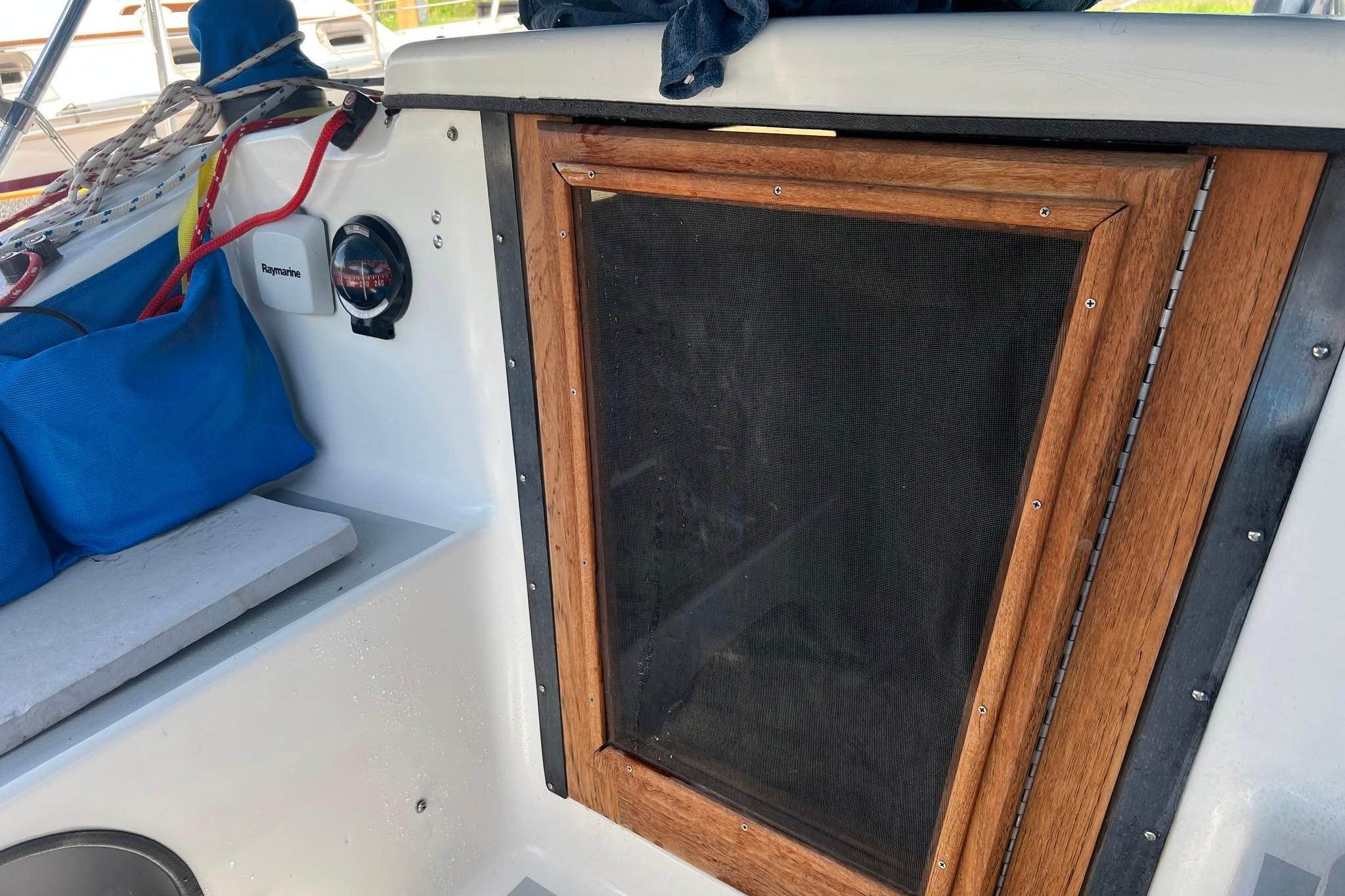 Cockpit of 1993 Corsair F-27 sailboat with wooden hatch and nautical equipment.