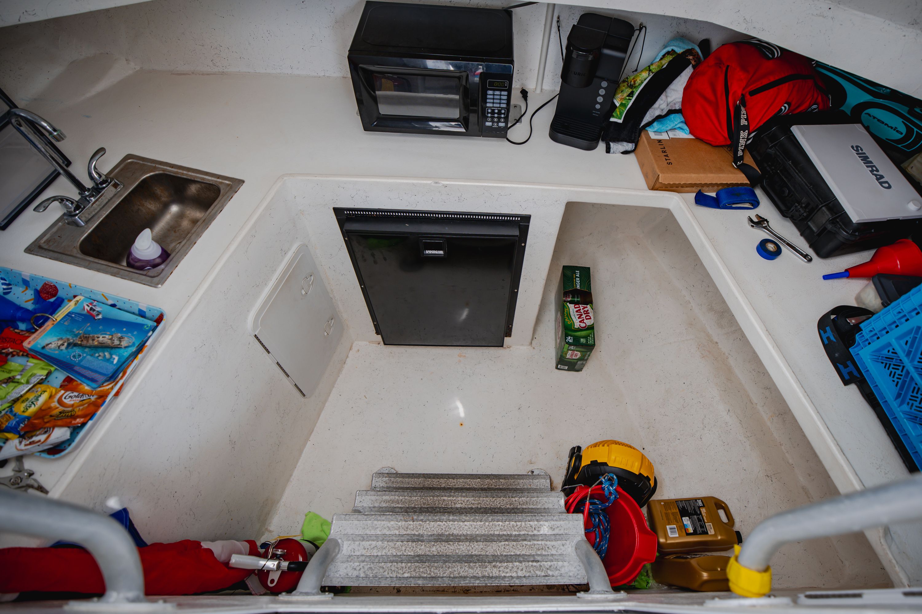 Small galley with microwave, sink, and fridge on a boat.