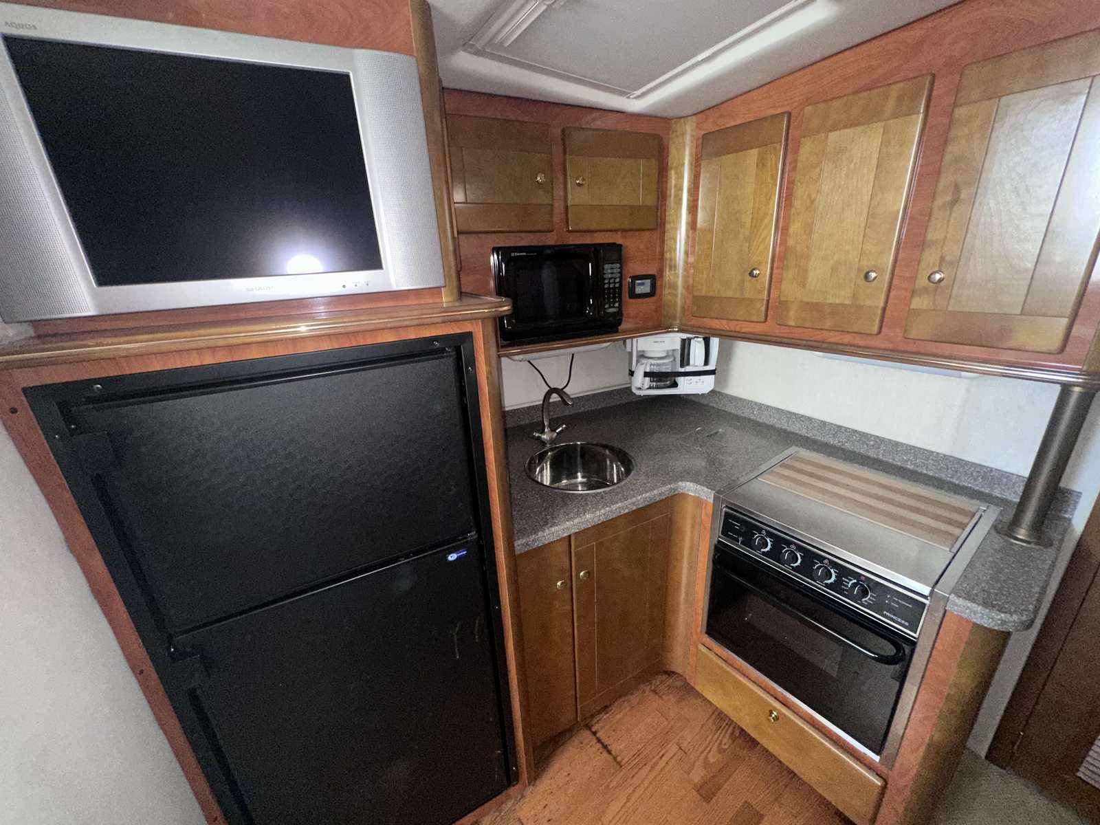 2004 Rinker Fiesta Vee 410 kitchen with appliances, wooden cabinets, and countertop.