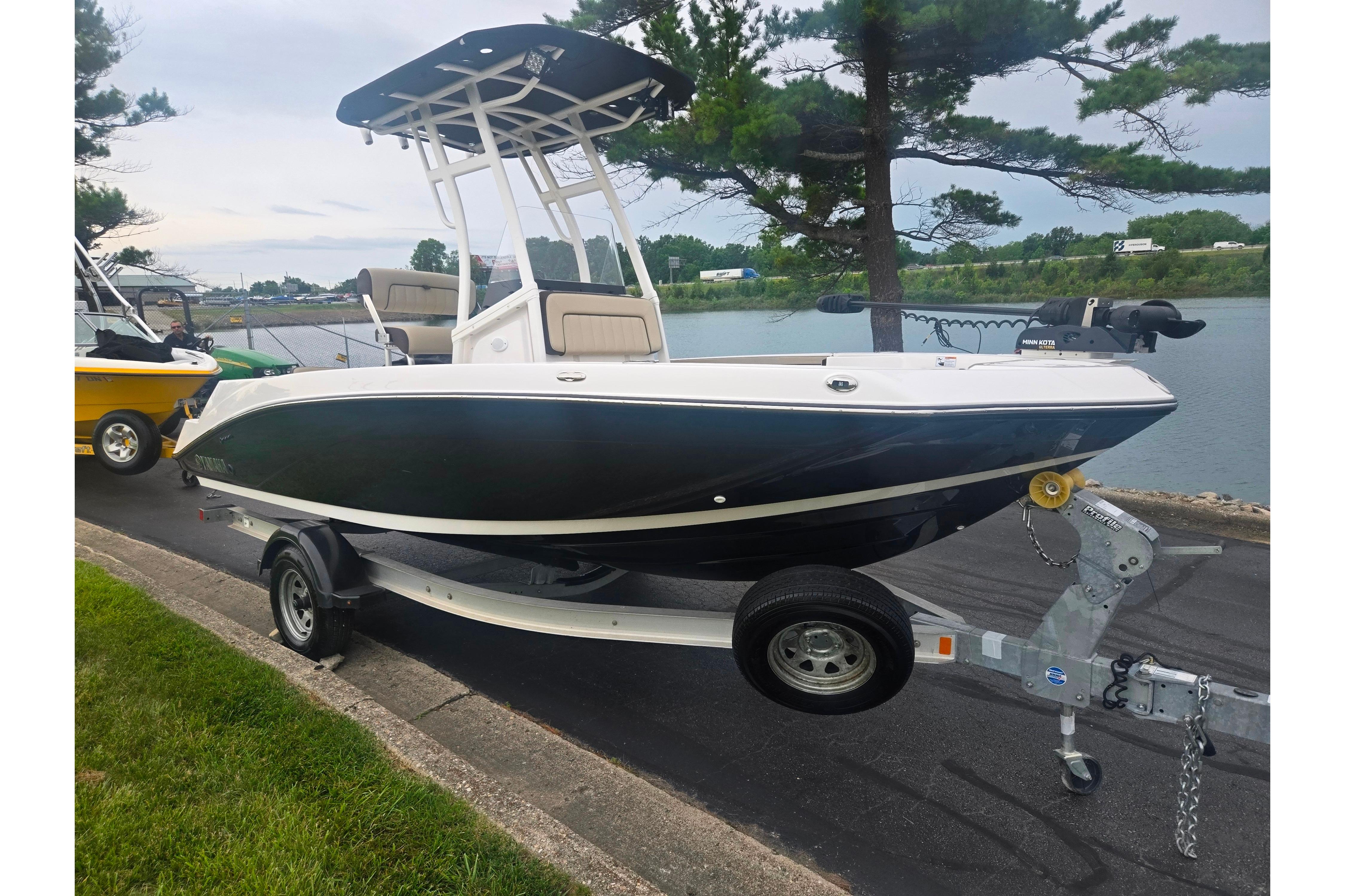 2022 Yamaha Boats 195 FSH Sport on trailer by a lakeside road.