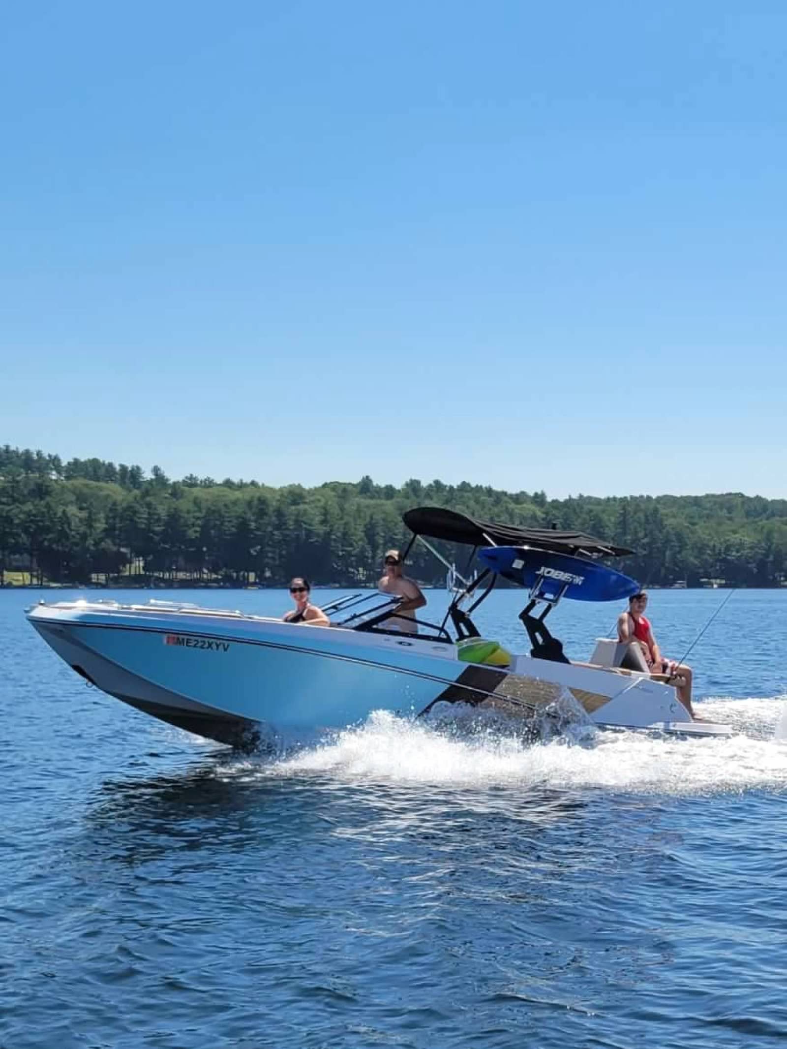 A 2019 Glastron GTDW 225 cruising on a lake. Three people are enjoying the ride.
