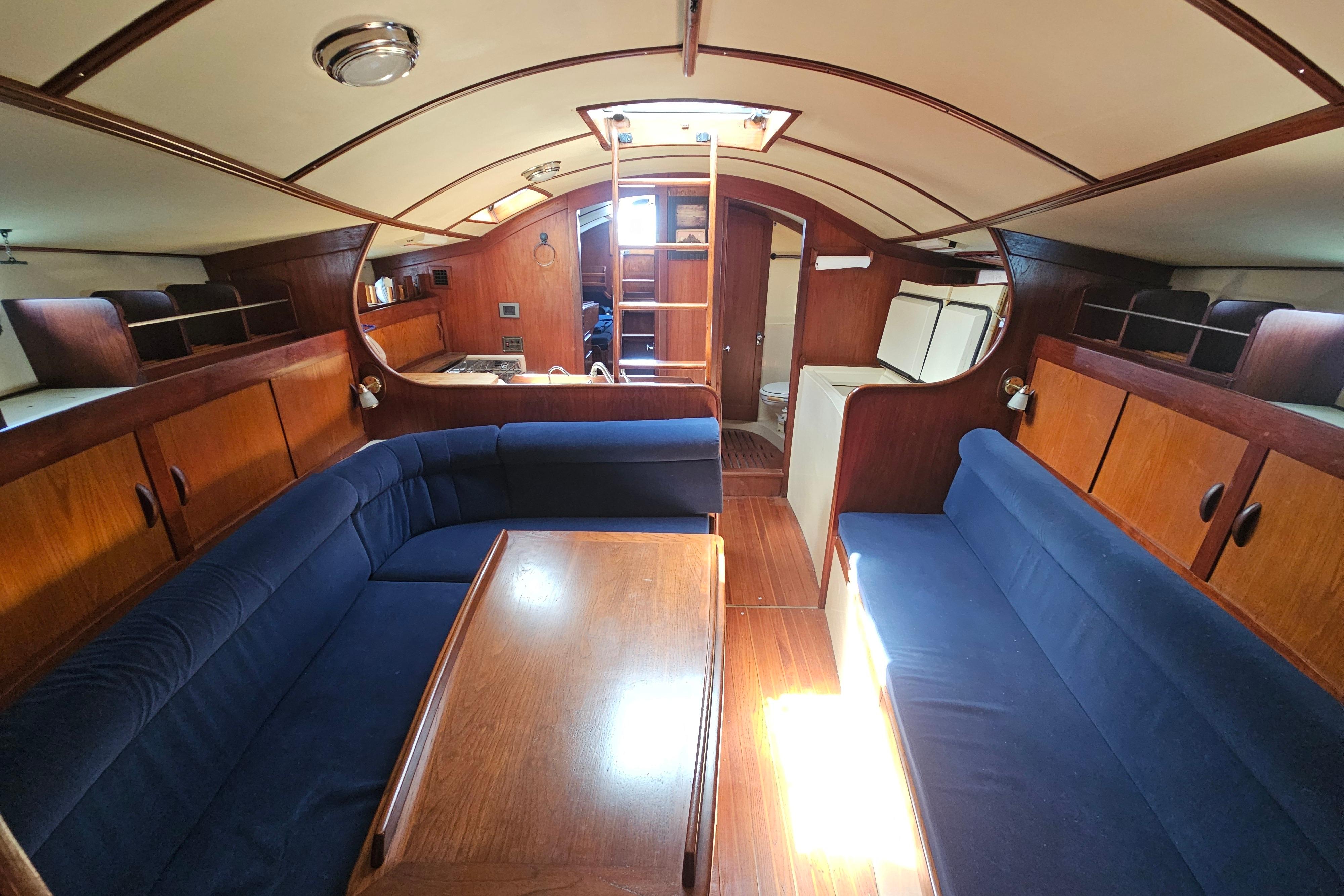 Interior of 1980 Tillotson-Pearson Freedom 40 sailboat with wooden furnishings and blue seating.