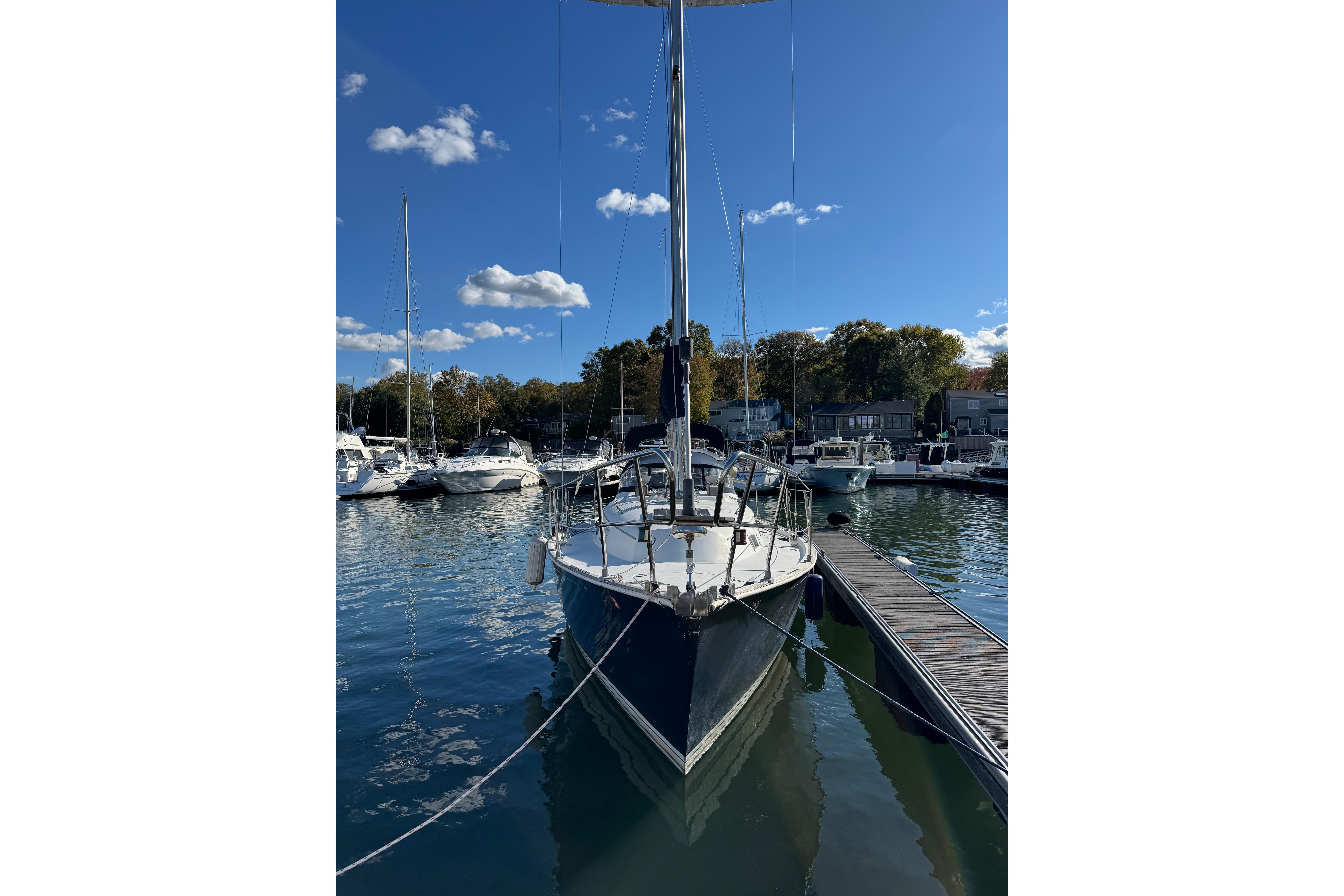 1984 C&C Landfall sailboat docked in a marina under a clear blue sky.