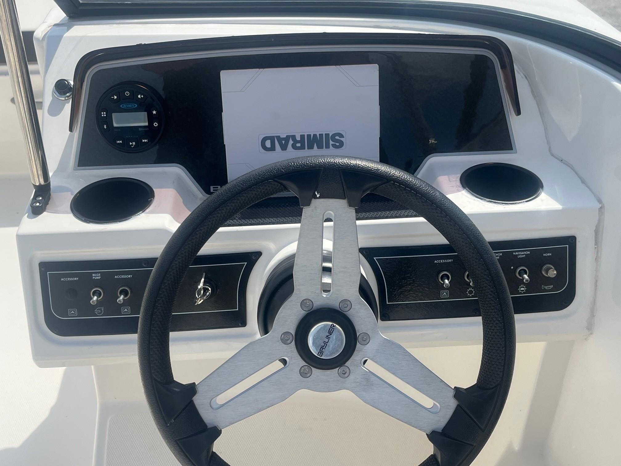 Steering wheel and dashboard of 2022 Bayliner DX 2200 boat, featuring controls and cup holders.