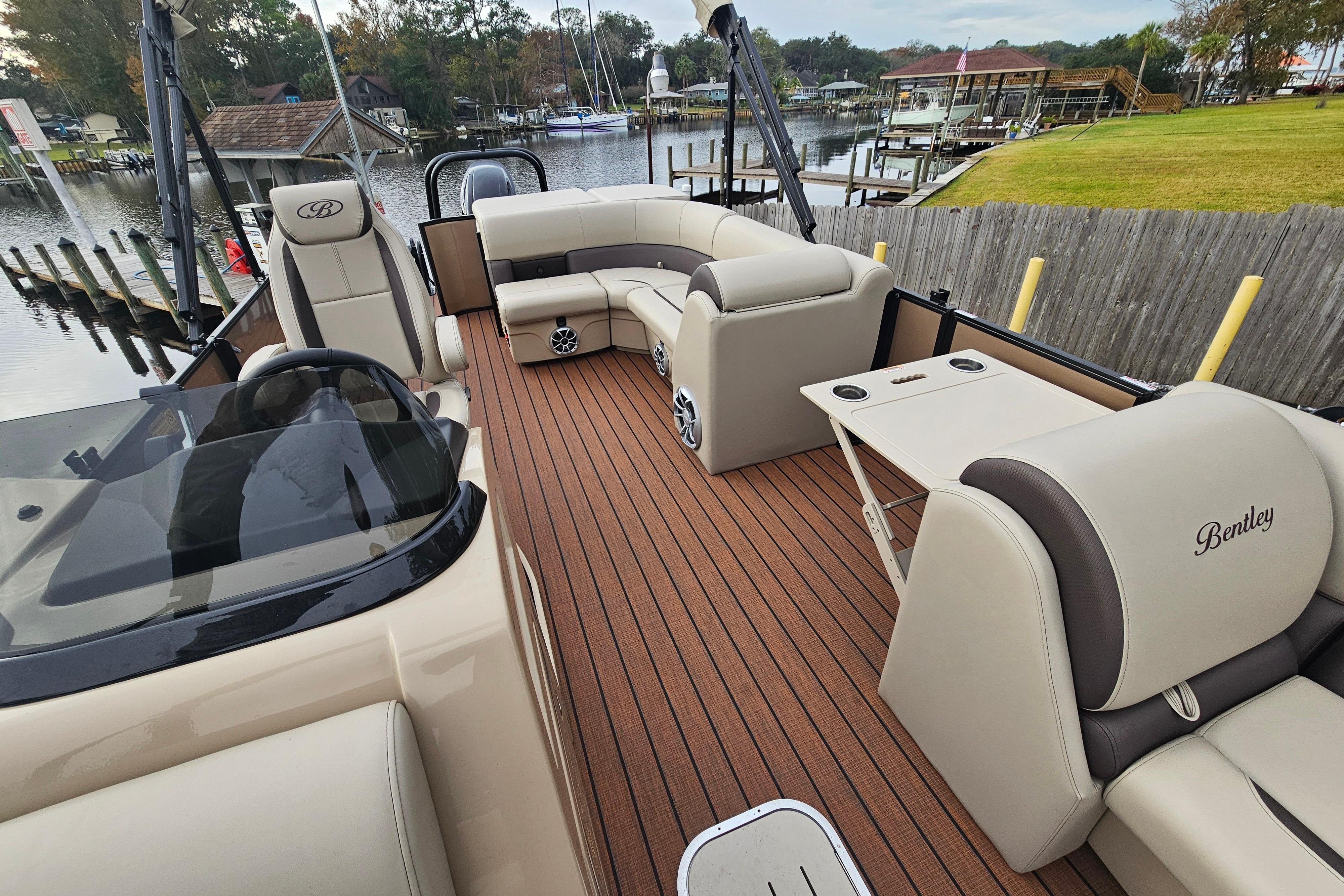 2026 Bentley Pontoons Legacy 243 Cruise with luxurious seating and sleek design on a scenic dock.