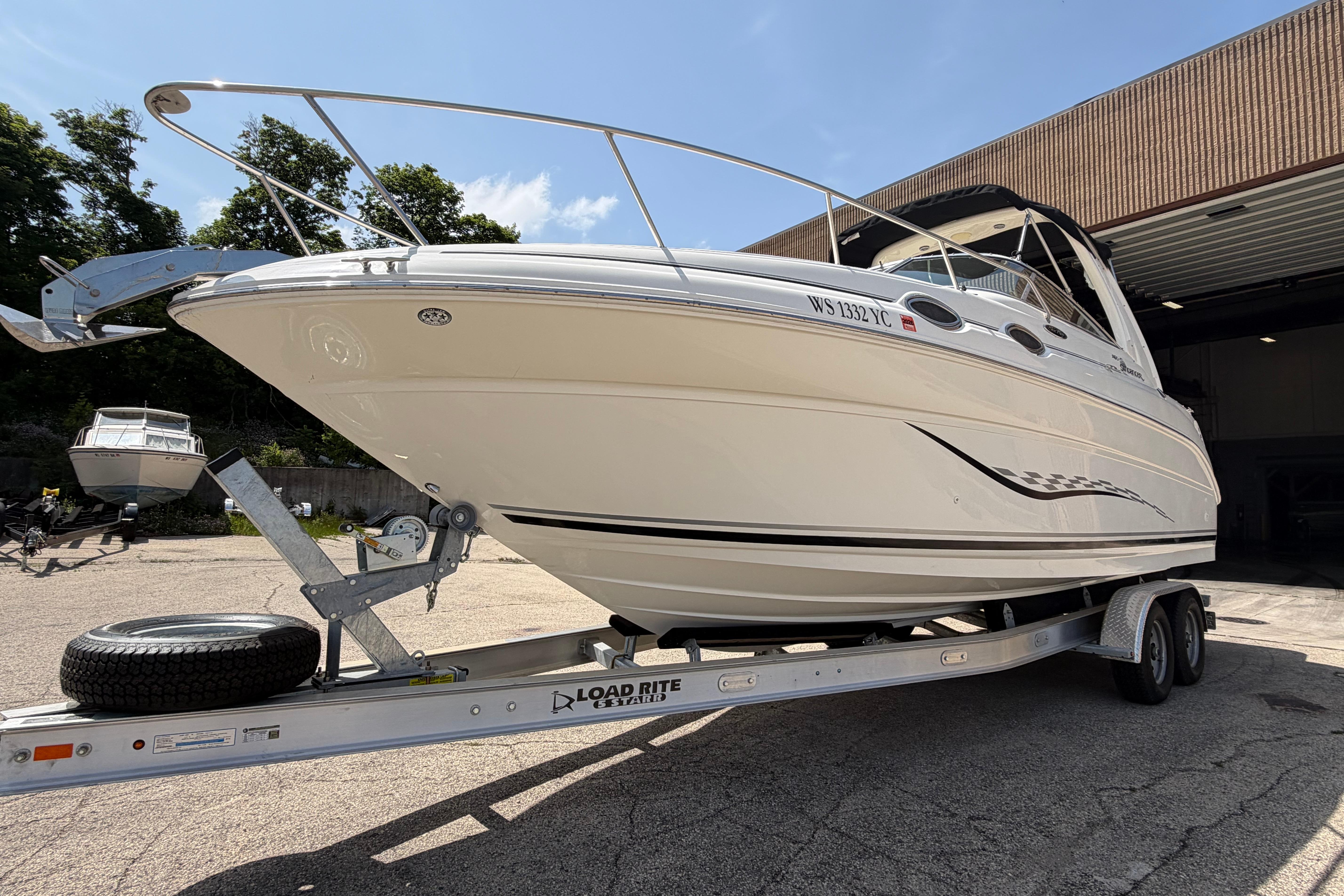 2004 Sea Ray Sundancer 260 on trailer, parked outdoors under clear sky.
