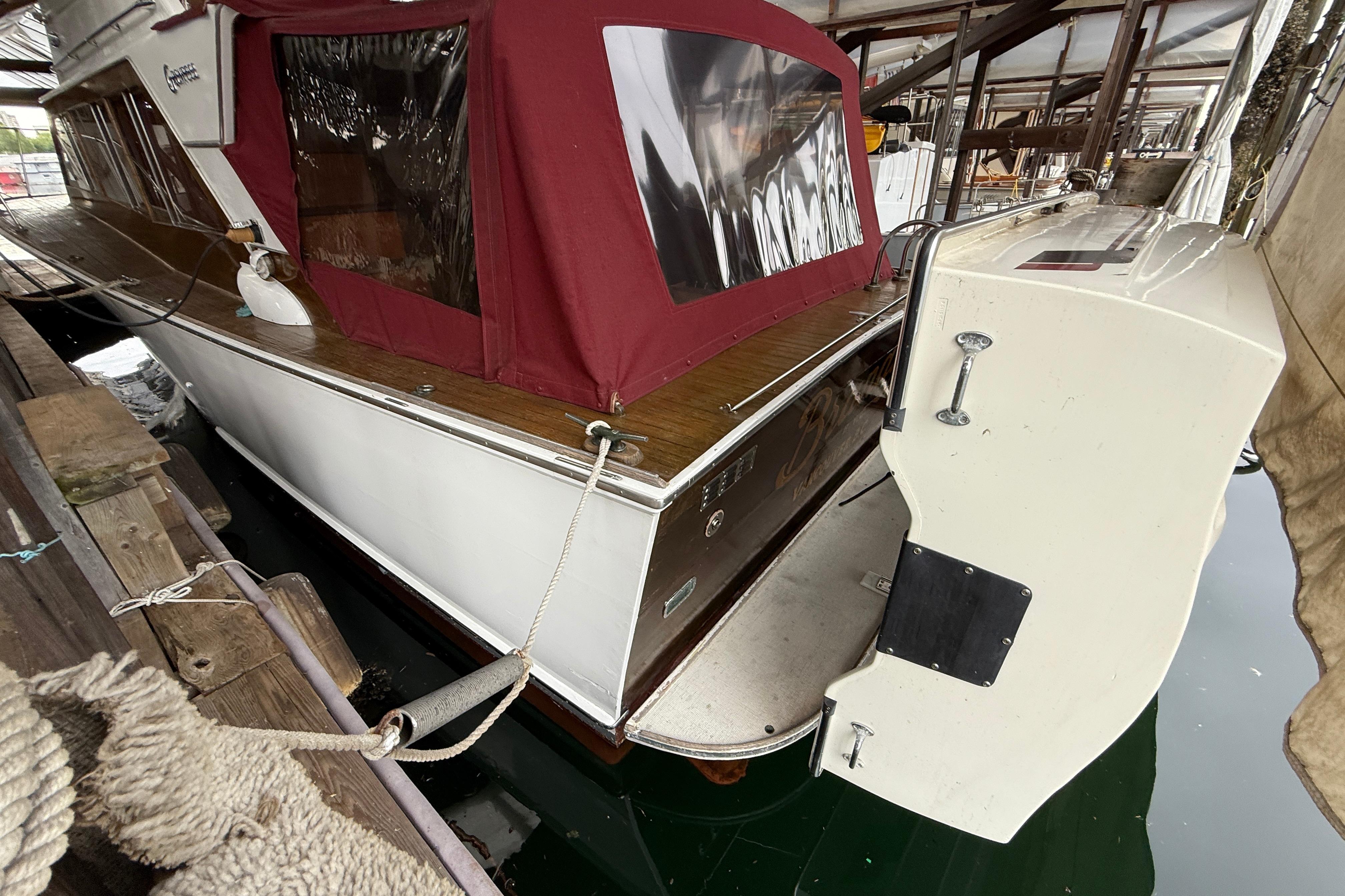 1963 Grenfell Command Bridge boat docked with maroon canopy and wooden deck.