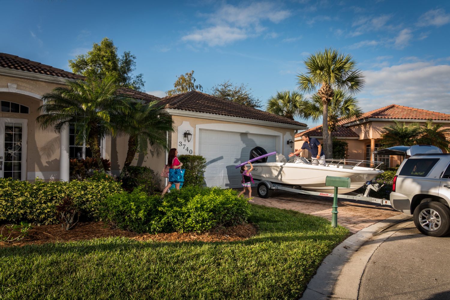 A family prepares to launch a Boston Whaler boat in the driveway.