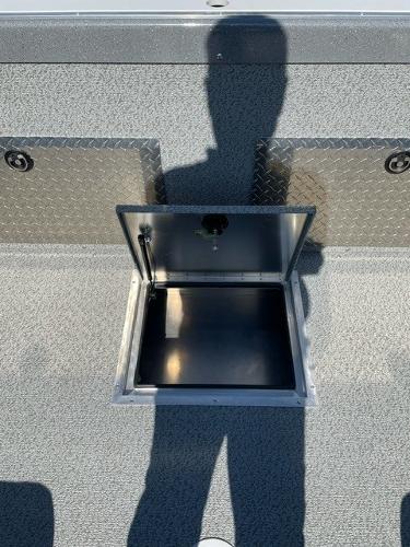 2025 Spartan 185 Astoria boat storage compartment with open hatch, textured flooring, and shadow.
