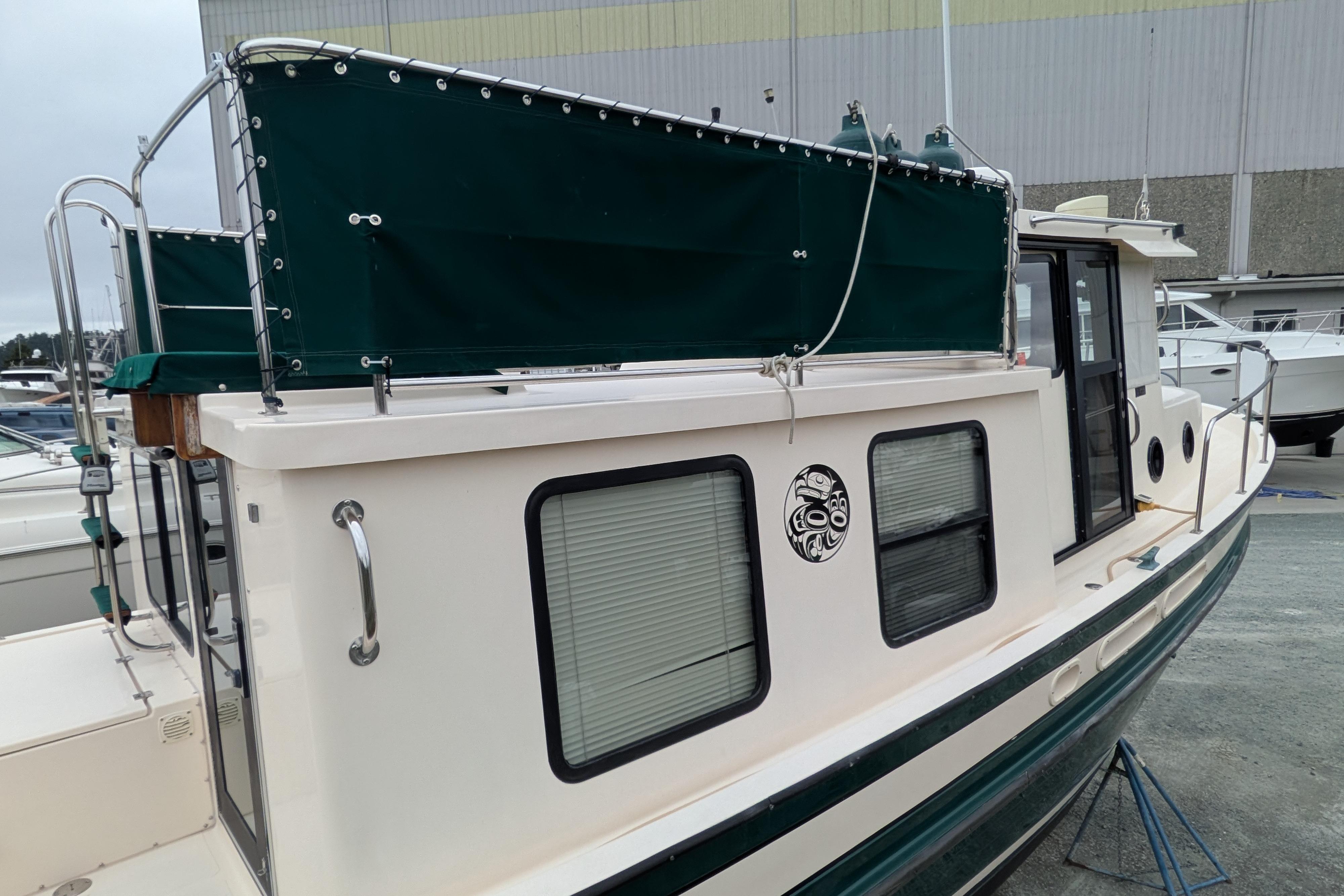 1998 Nordic Tug 32 boat with green canopy and distinctive window design.