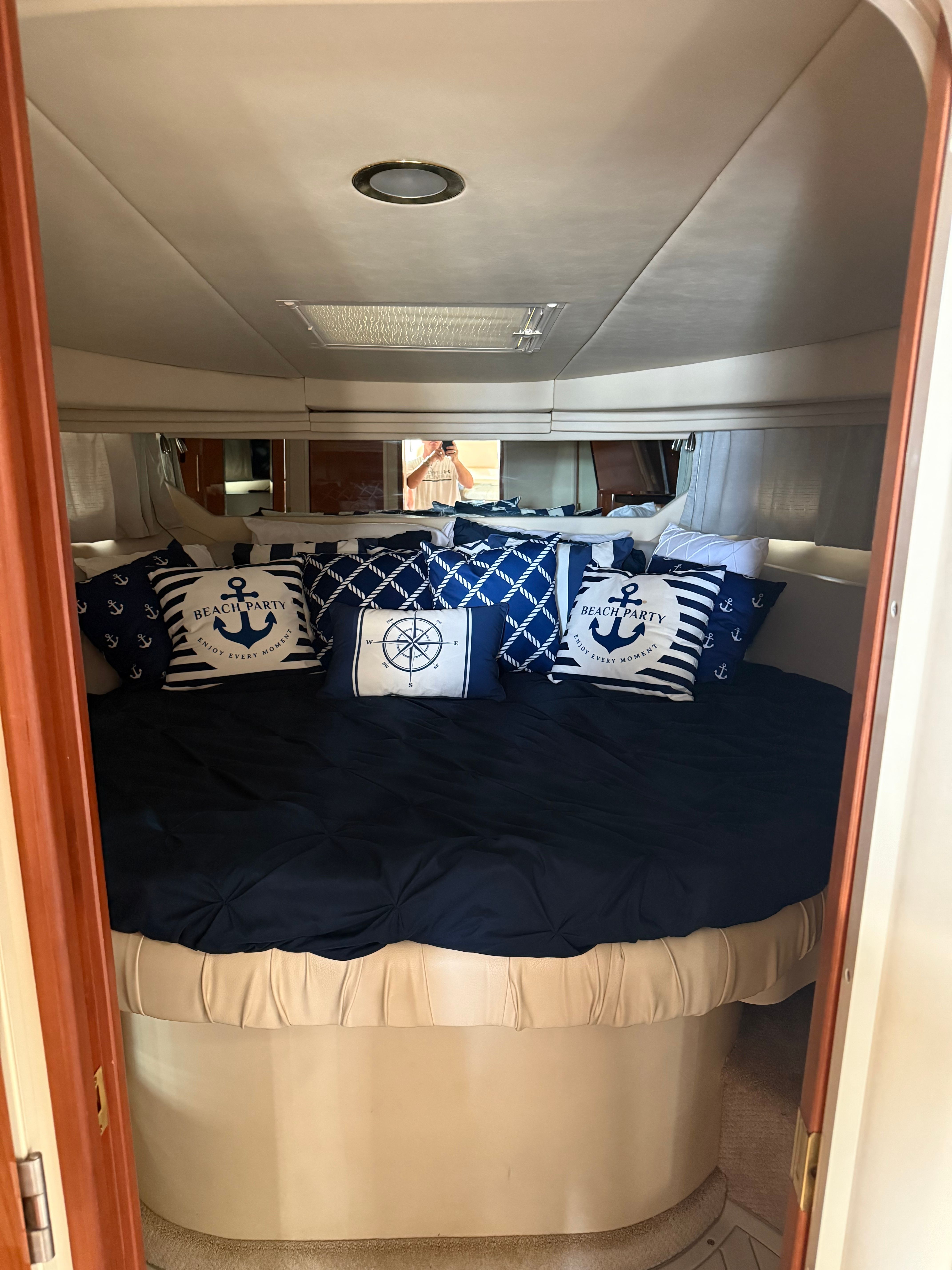 Interior of a Sea Ray 380 Sundancer with nautical-themed pillows on a round bed.