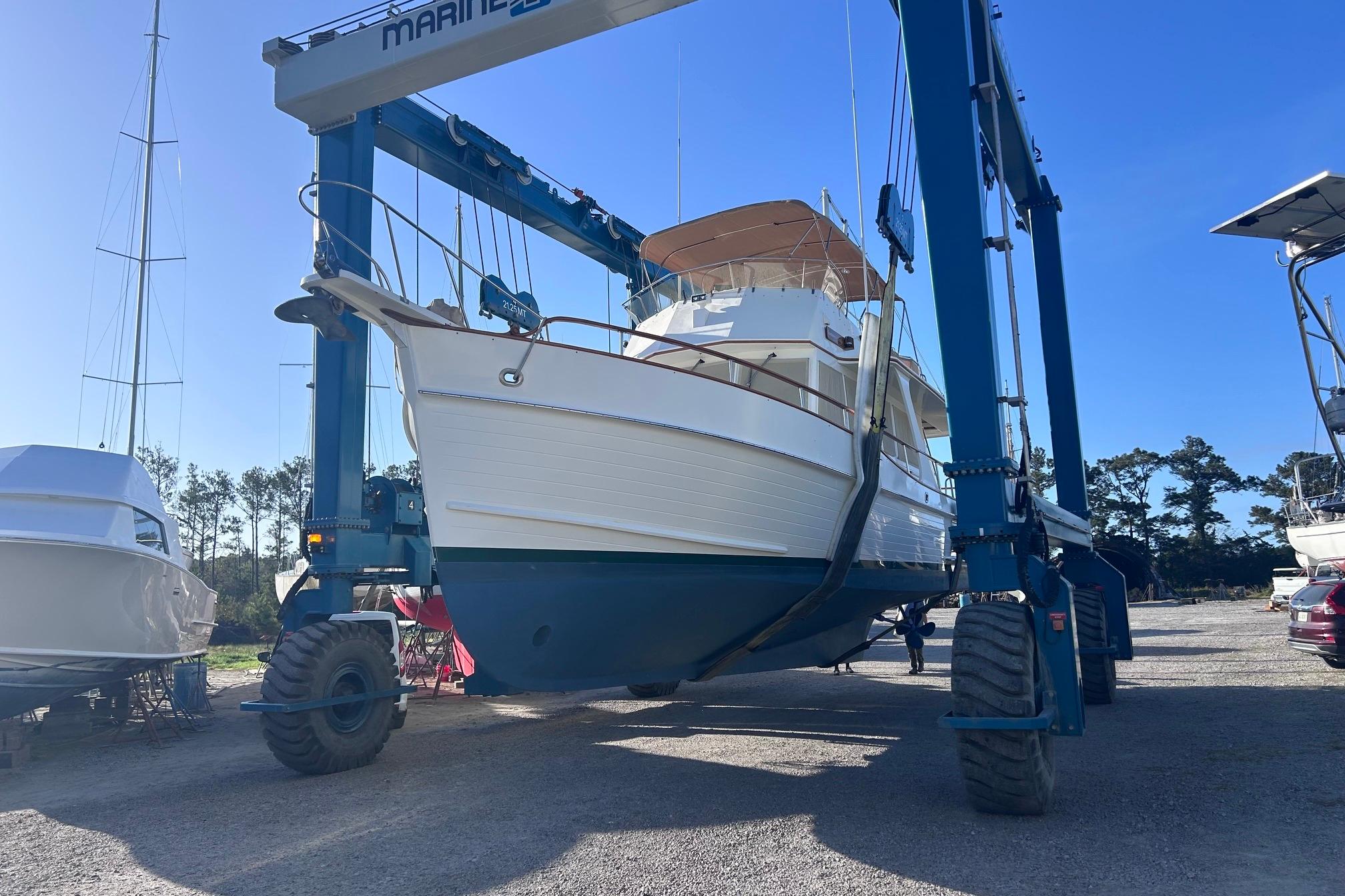 1999 Grand Banks 42 Europa yacht lifted by a marine travel lift in a boatyard.