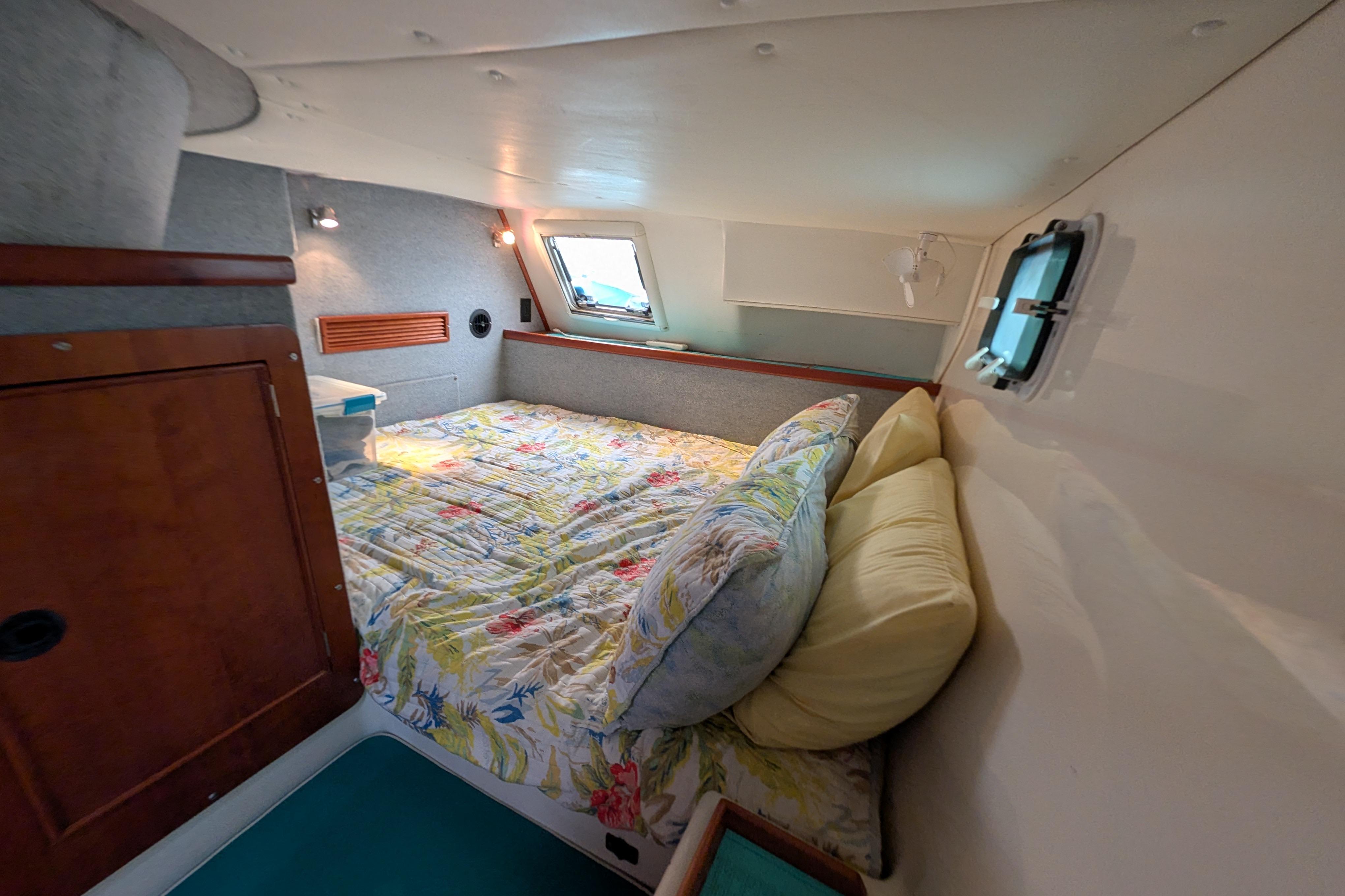 Cozy cabin interior of 2004 PDQ 34 Powercat with floral bedding and porthole window.