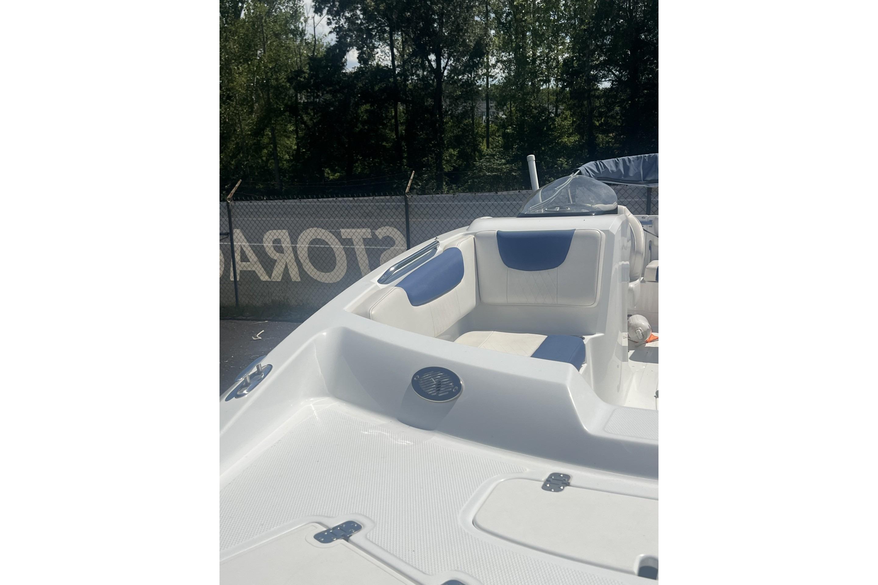 2017 Tahoe 2150 boat interior with white and blue seating, parked outdoors.