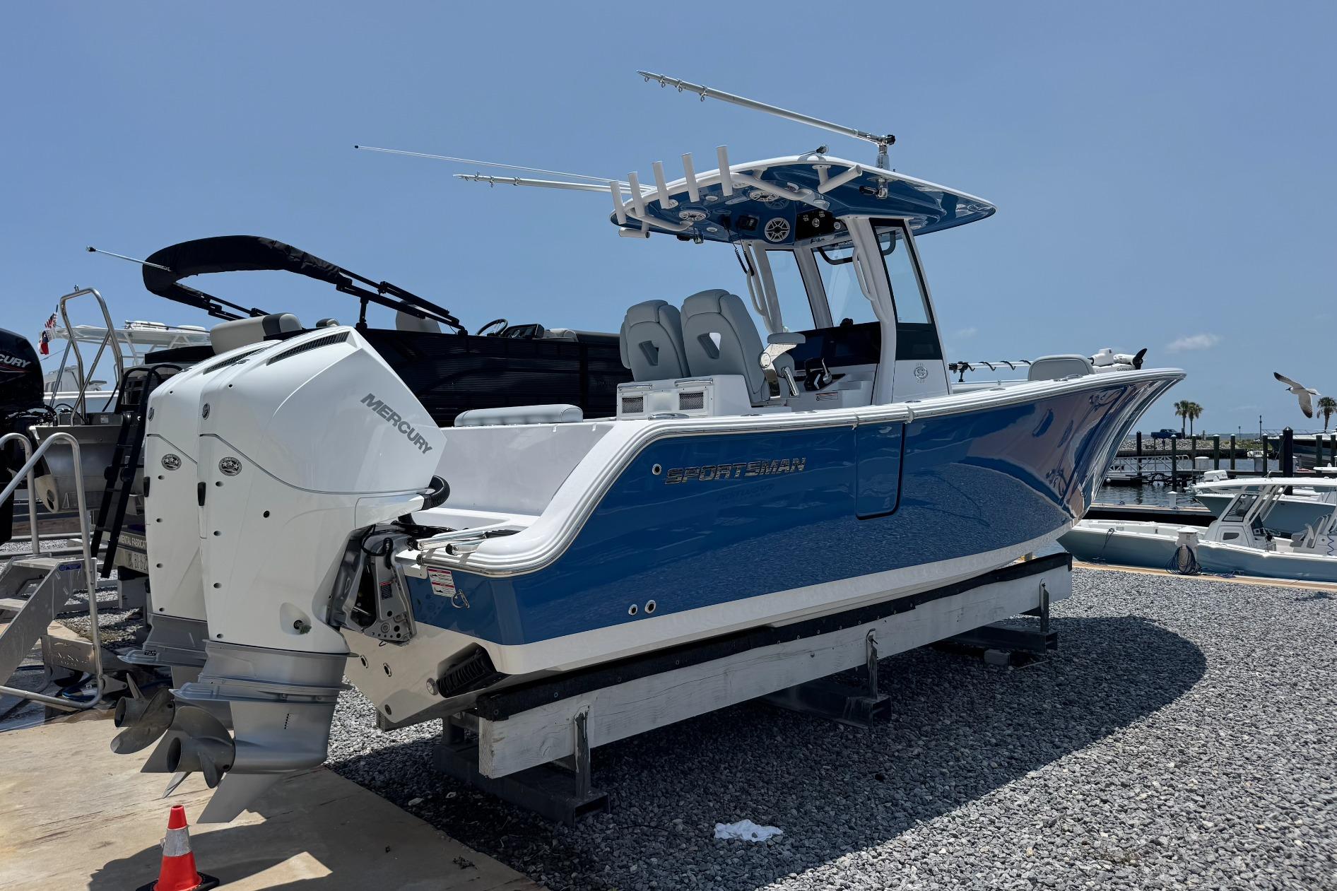 2026 Sportsman Open 262 Center Console boat with dual Mercury engines, docked on gravel.