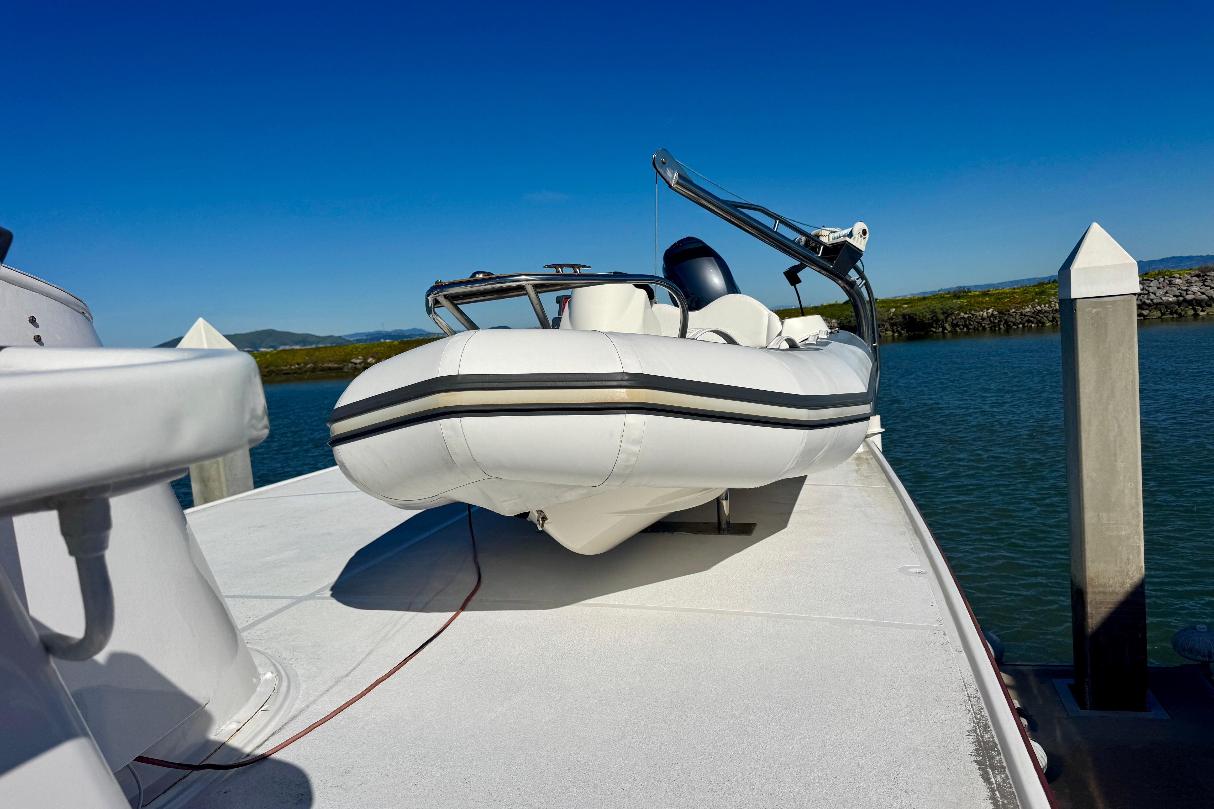 1958 Blanchard Pilothouse boat with inflatable dinghy on deck, docked by calm waters.