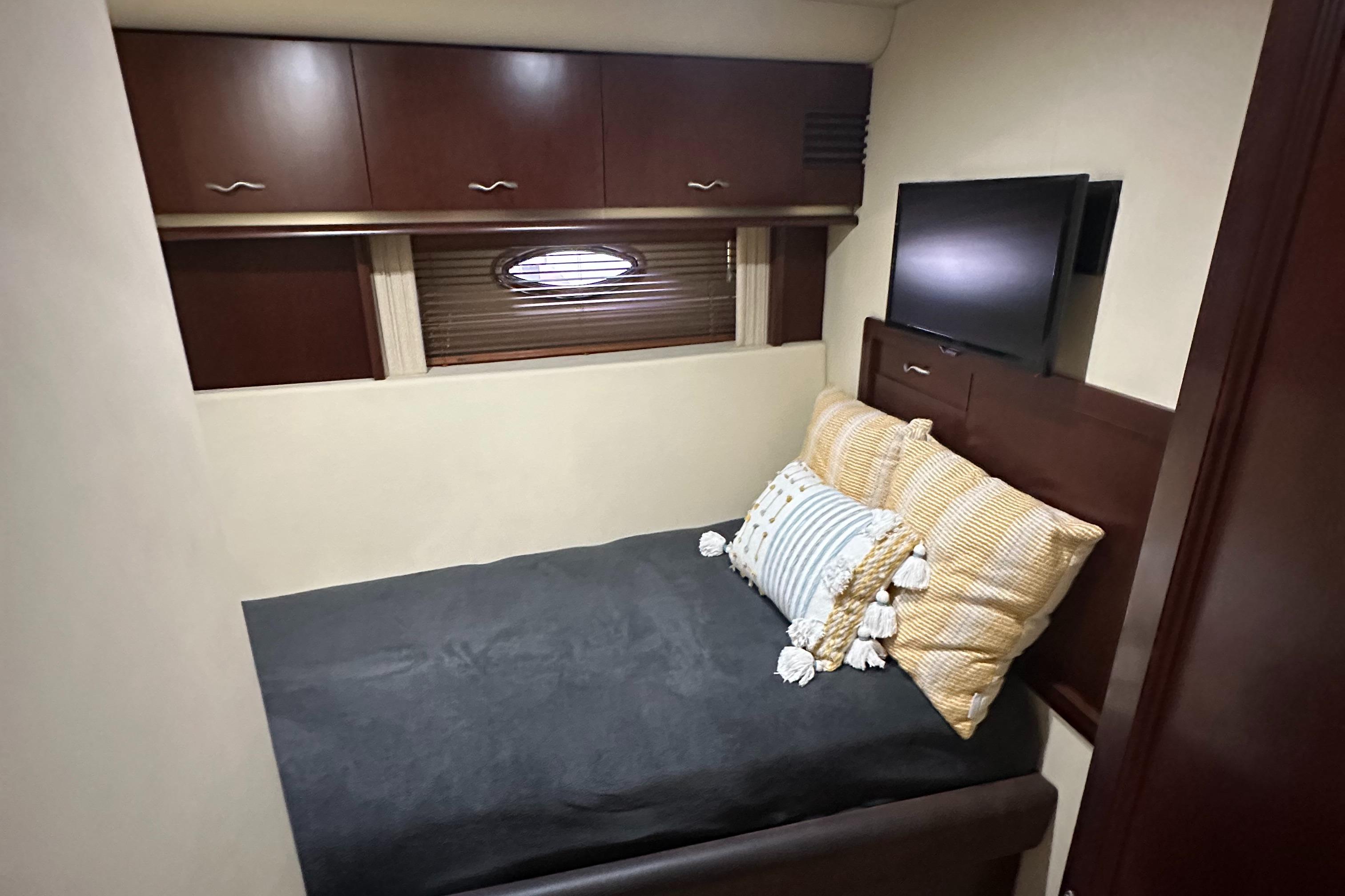 Luxurious cabin interior of 2006 Sea Ray 58 Sedan Bridge yacht with cozy bed and TV.