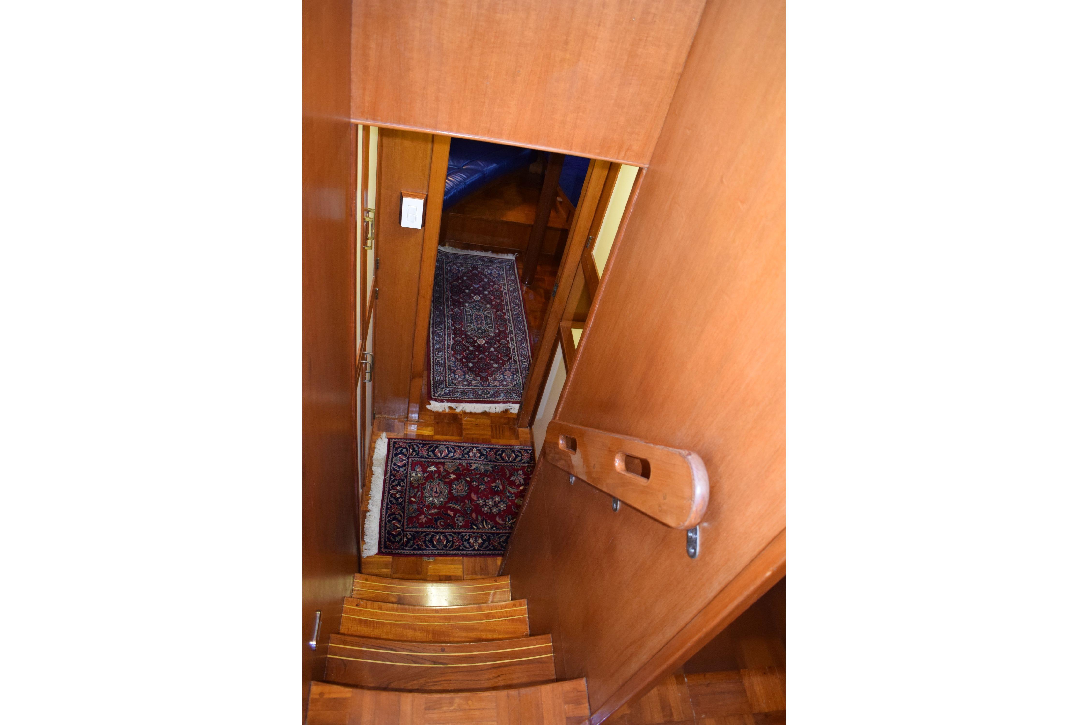 Interior staircase of 1980 Cheoy Lee 52 Motorsailer with wooden finish and decorative rugs.