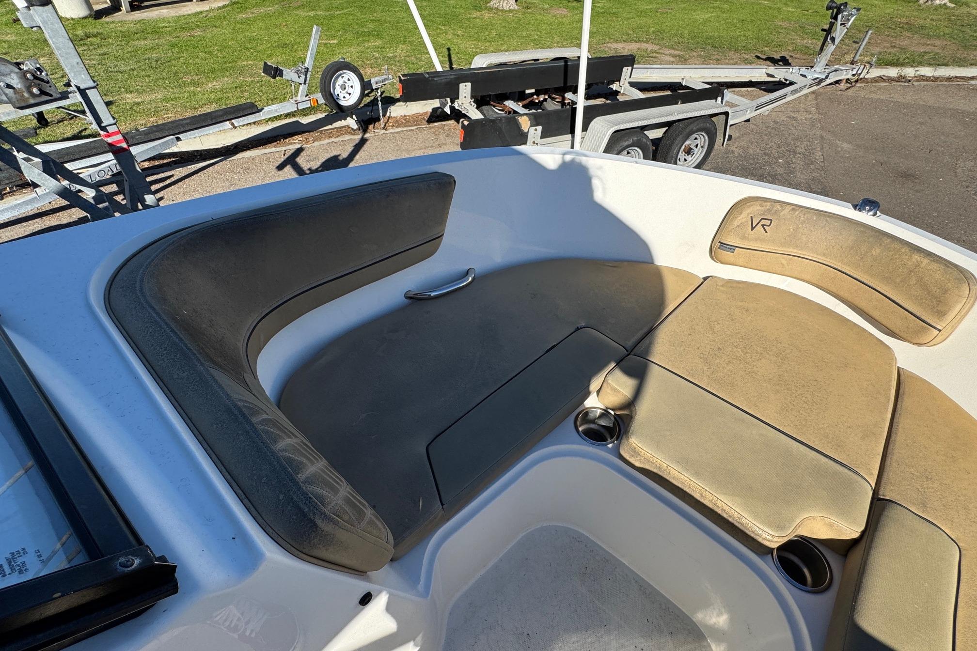 2022 Bayliner VR6 Bowrider OB interior seating with cup holders and trailer in background.