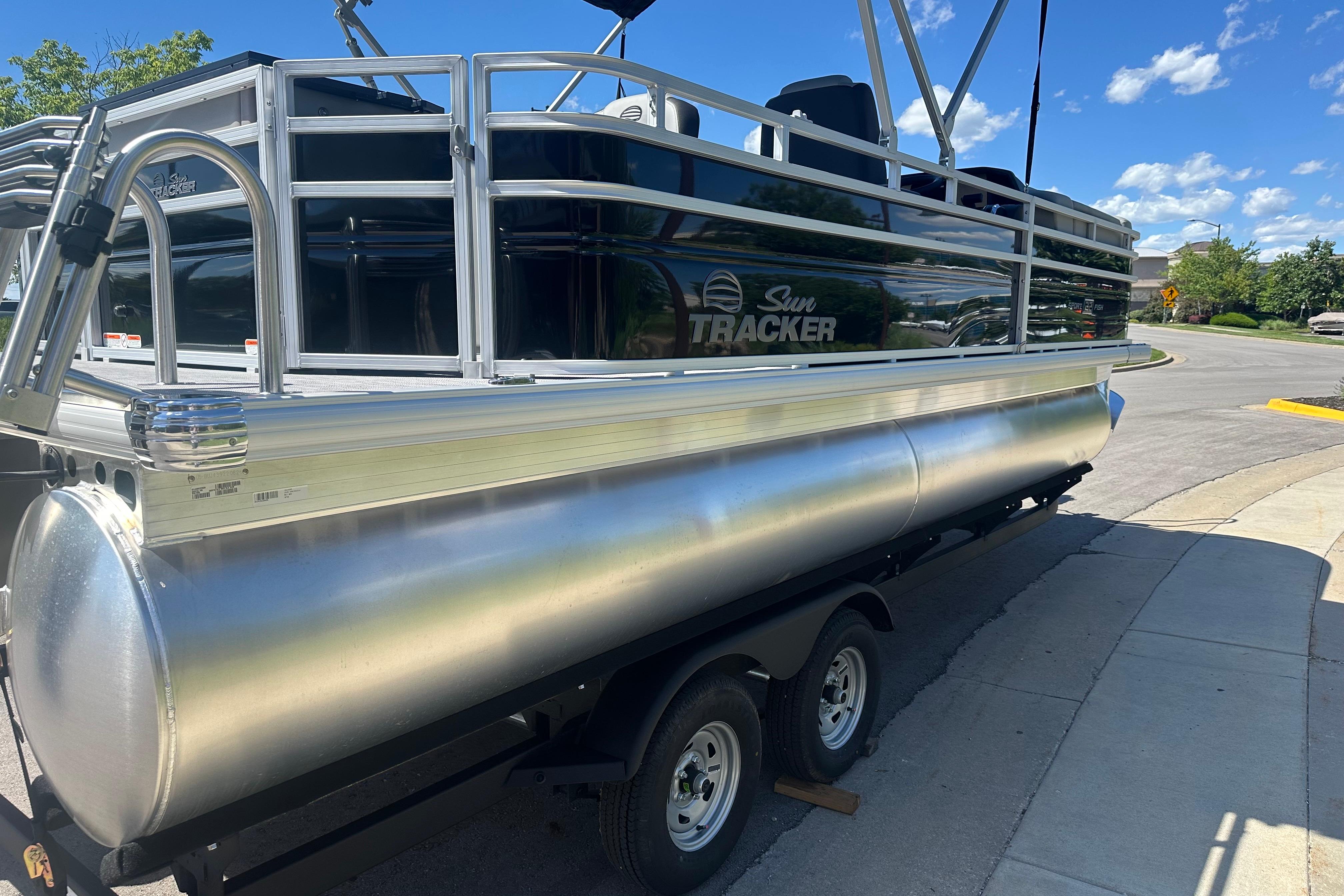 2026 Sun Tracker SportFish 22 DLX pontoon boat on trailer, parked on a sunny day.