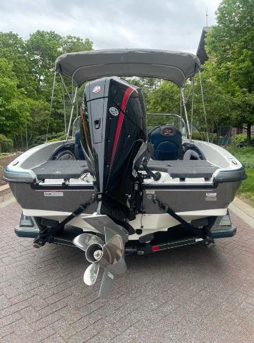 2025 Ranger 1850MS boat with outboard motor, parked on a paved path, surrounded by trees.