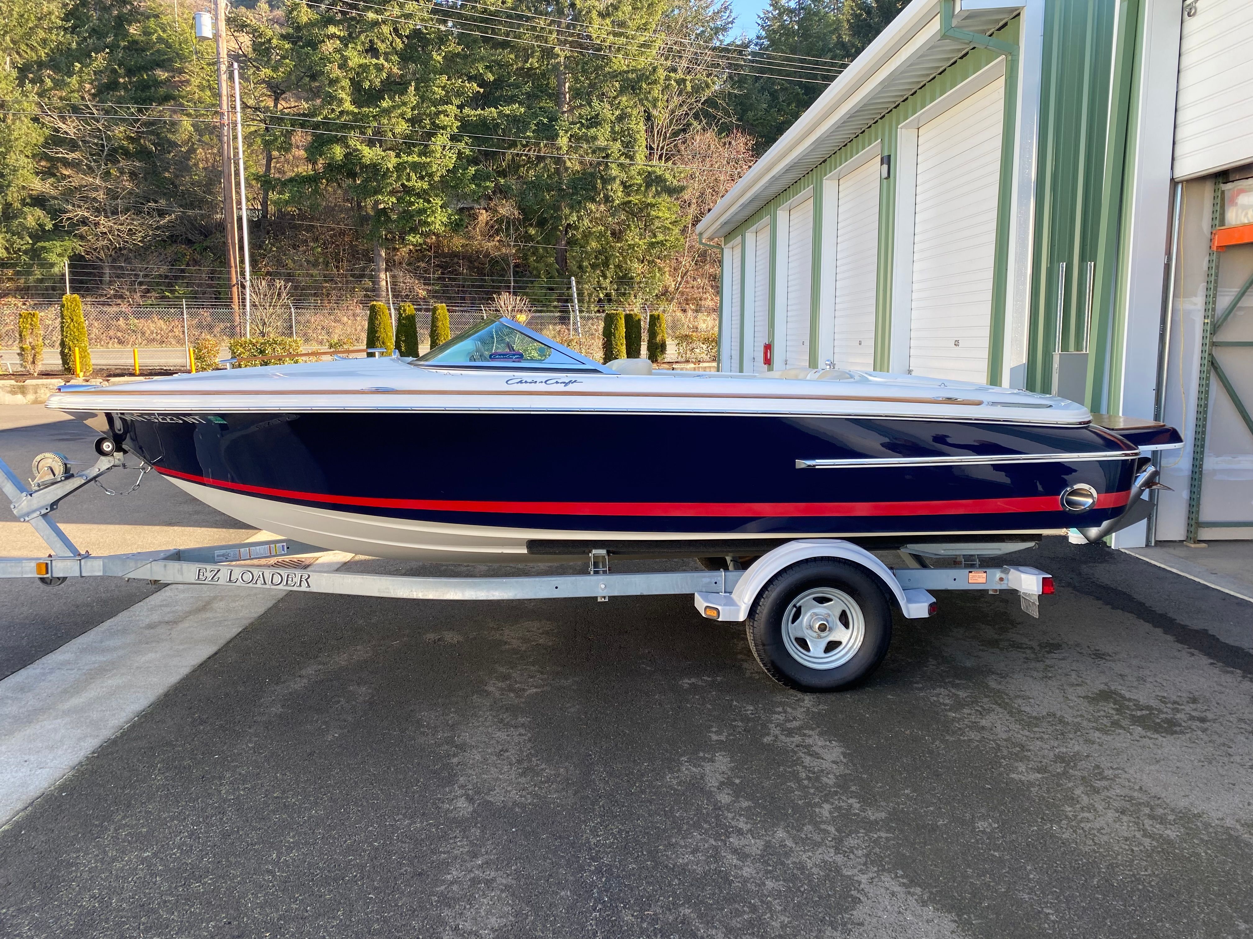 A 2006 Chris-Craft Speedster on a trailer, featuring a blue hull with red accents.