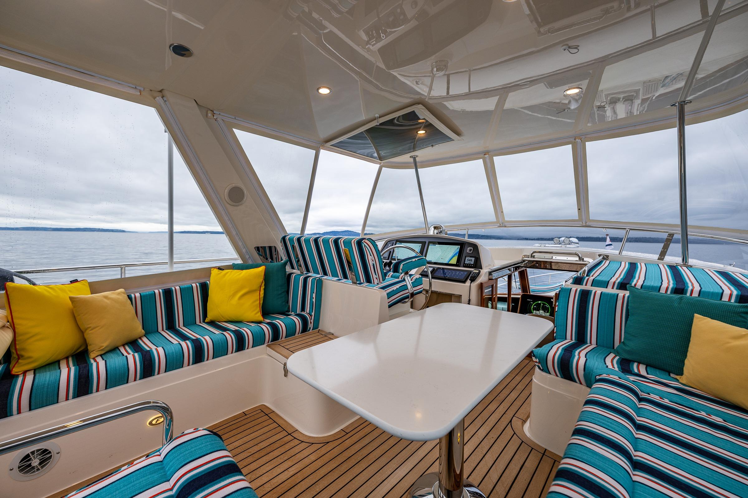 Luxurious 2026 Fleming 55 Pilothouse interior with striped seating, vibrant cushions, and panoramic ocean views.