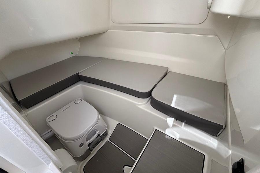 Interior cabin of 2027 Sea Ray SDX 230 Outboard with seating and portable toilet.