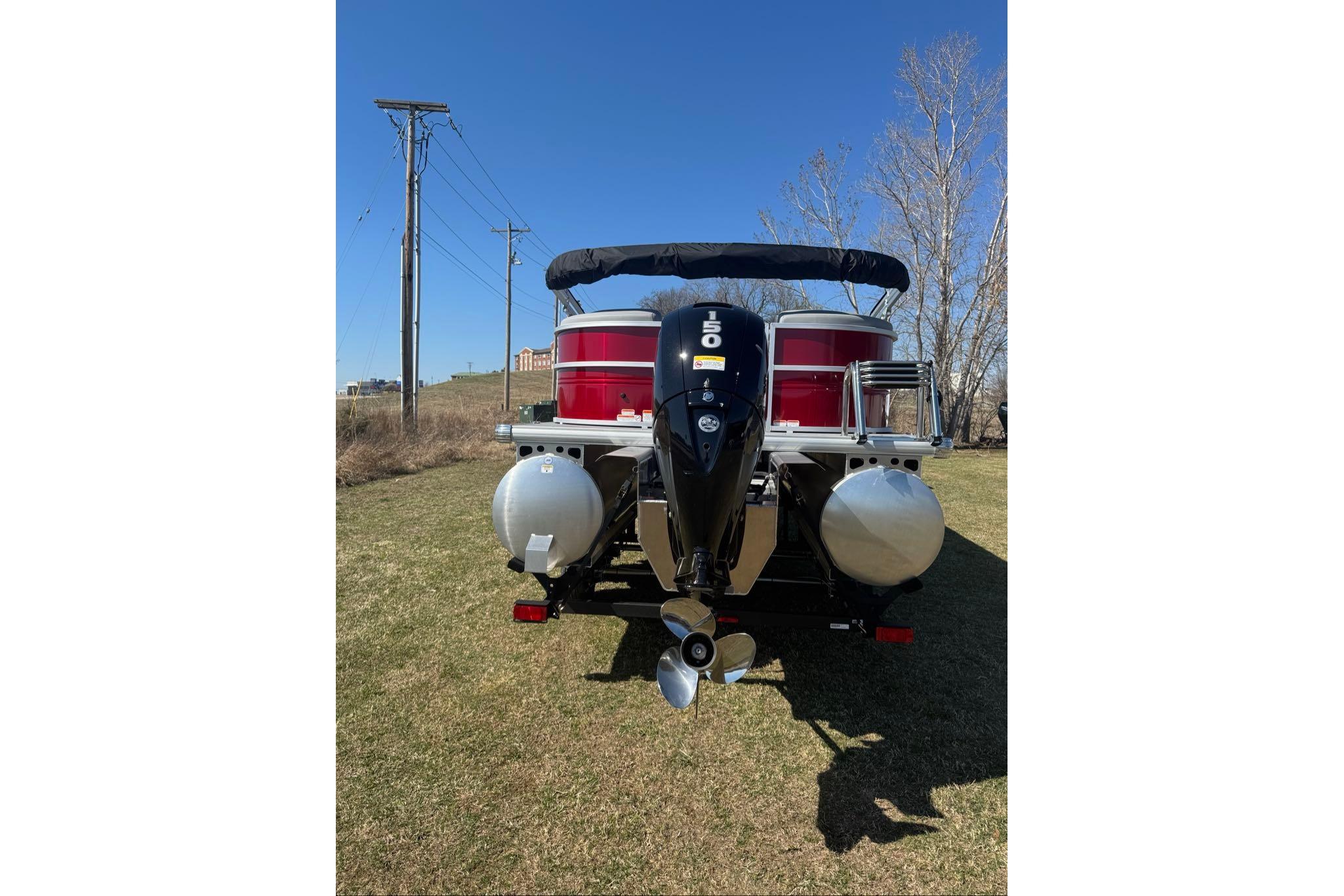 2026 Sun Tracker Party Barge 22 XP3 pontoon boat with powerful outboard motor, parked on grass.