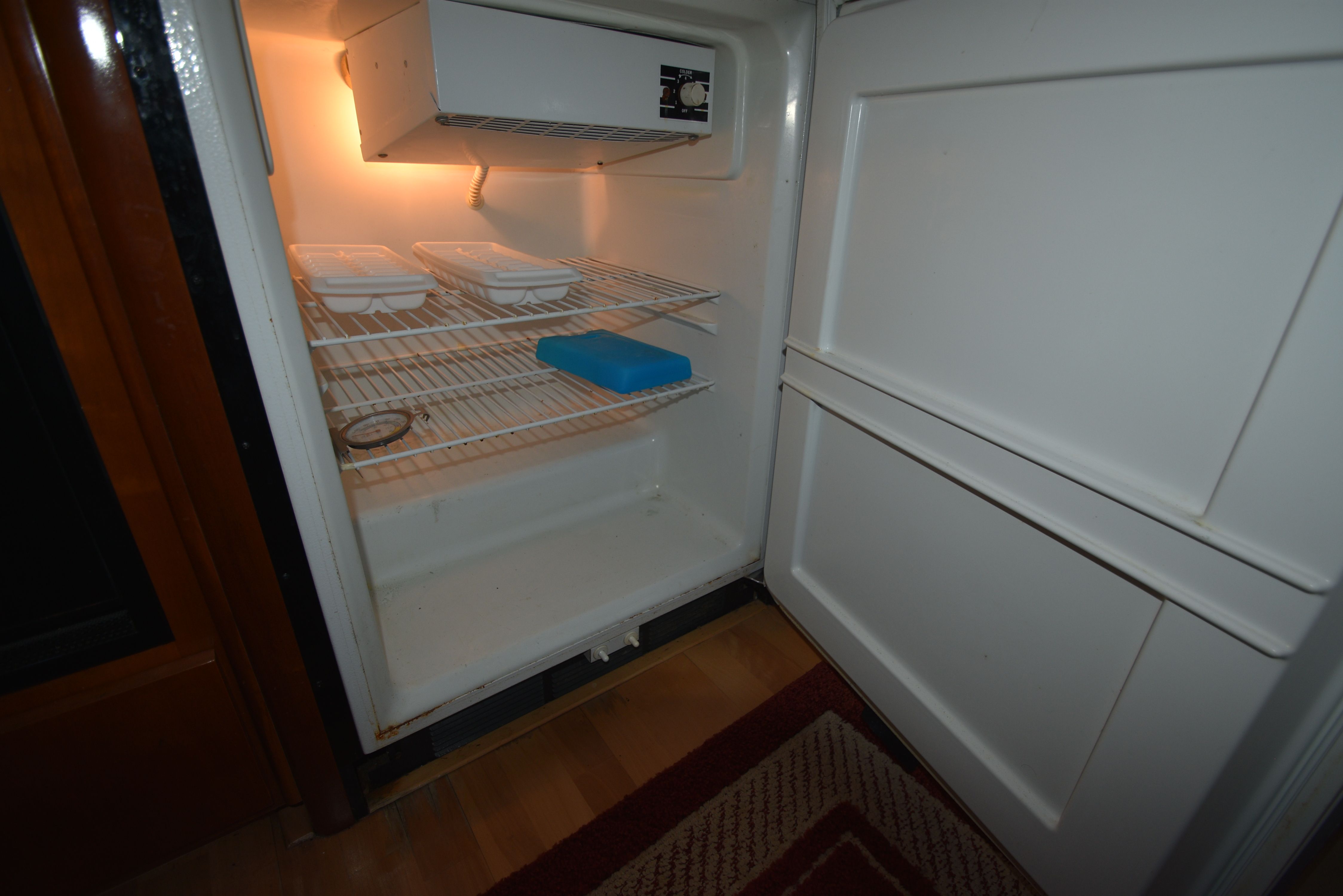 An open refrigerator with empty shelves and a blue container inside.