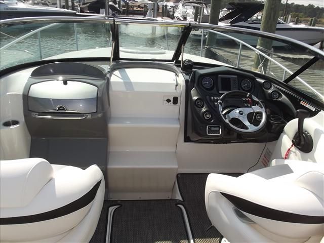The cockpit of a modern boat with white seats and a black steering wheel.