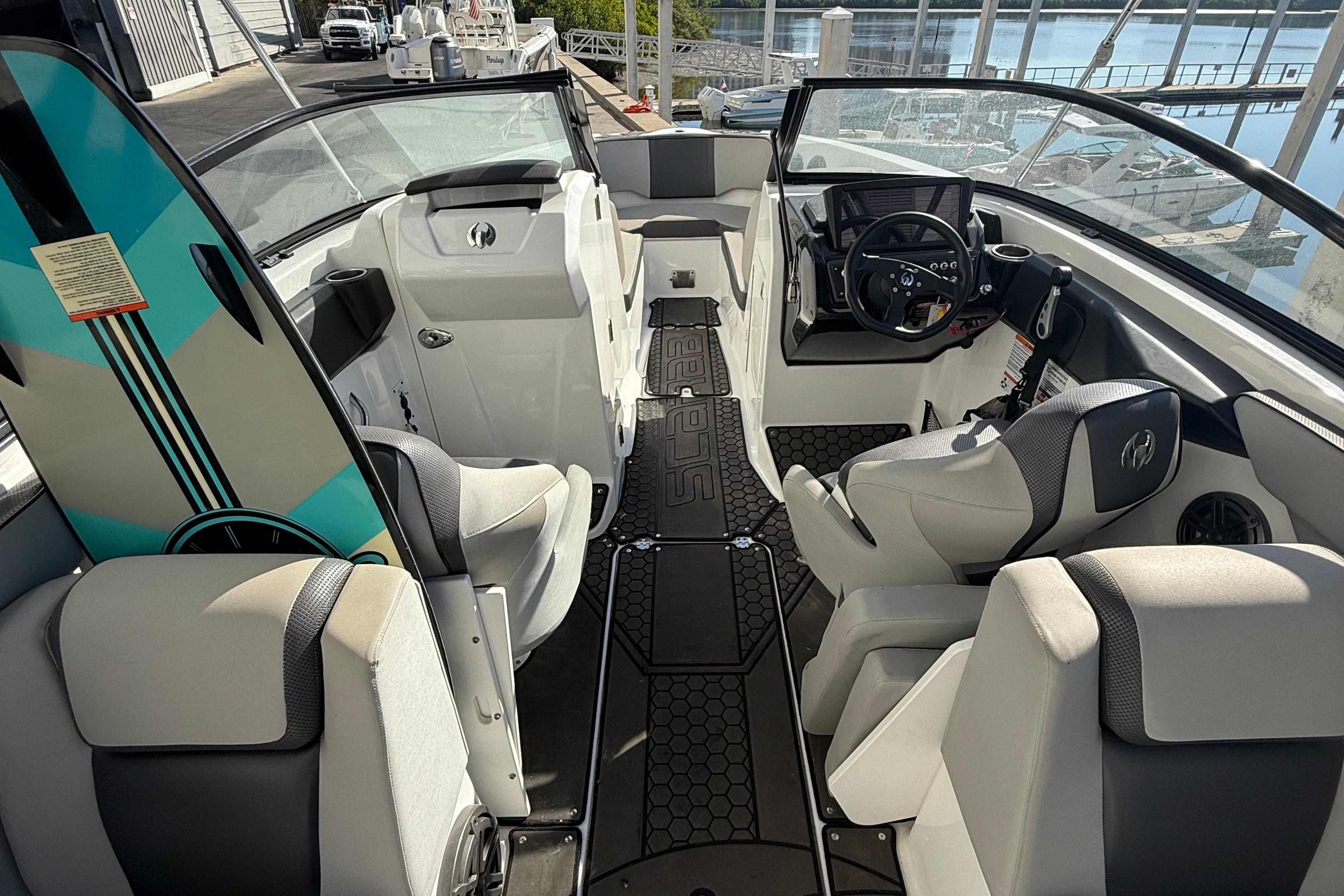 2021 Scarab 255 ID boat interior with seating, steering wheel, and surfboard.